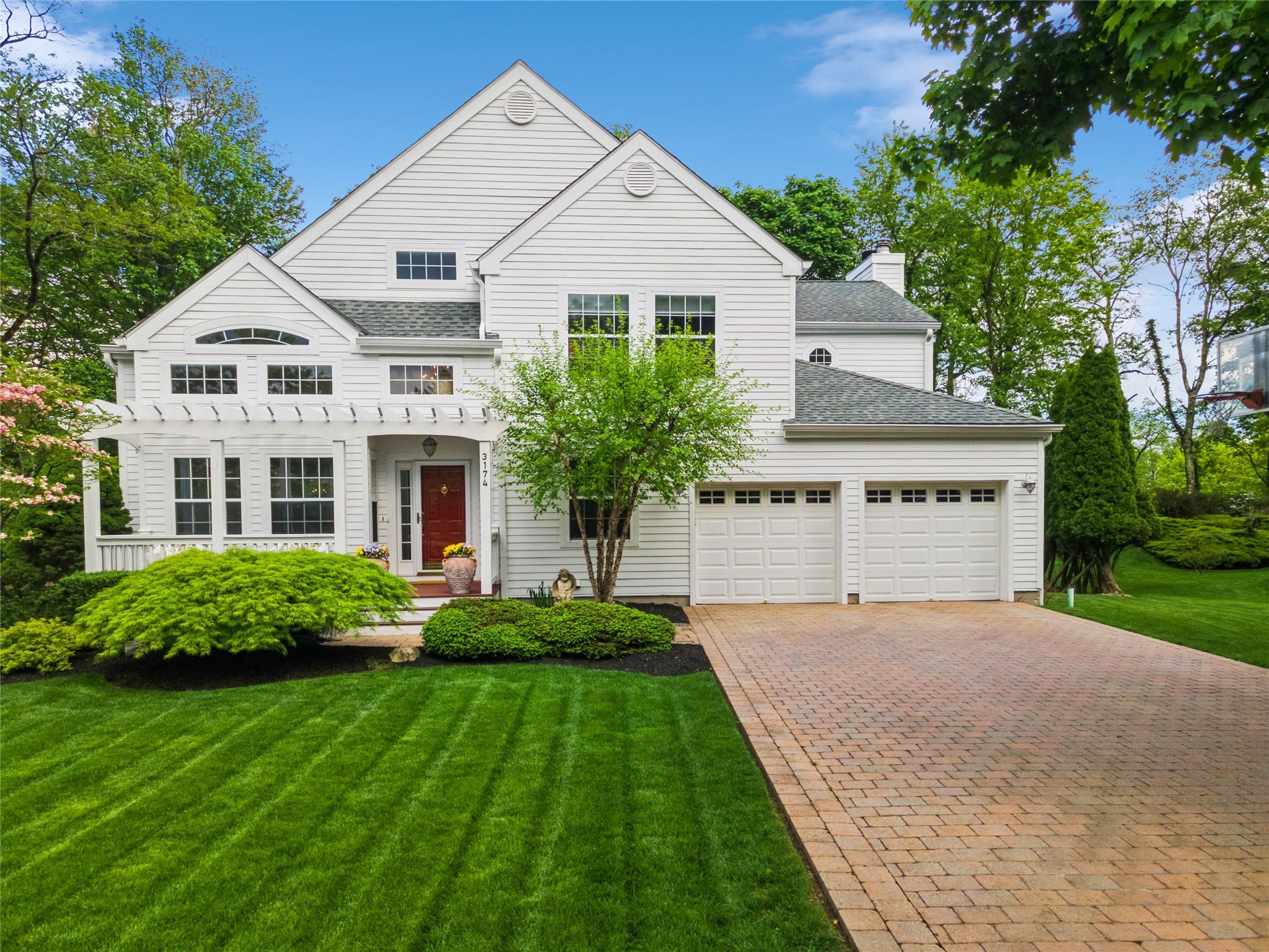 View of front of property featuring roof with asphalt shingles, concrete paver driveway,  a front lawn and attached garage