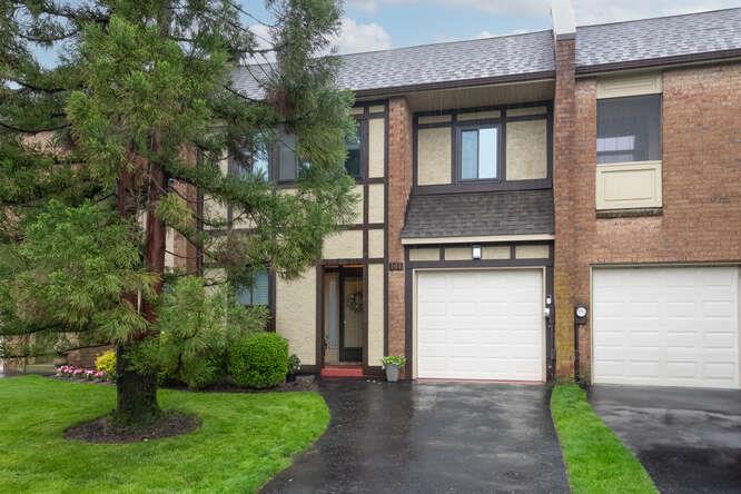Multi unit property featuring a shingled roof, asphalt driveway, and an attached garage