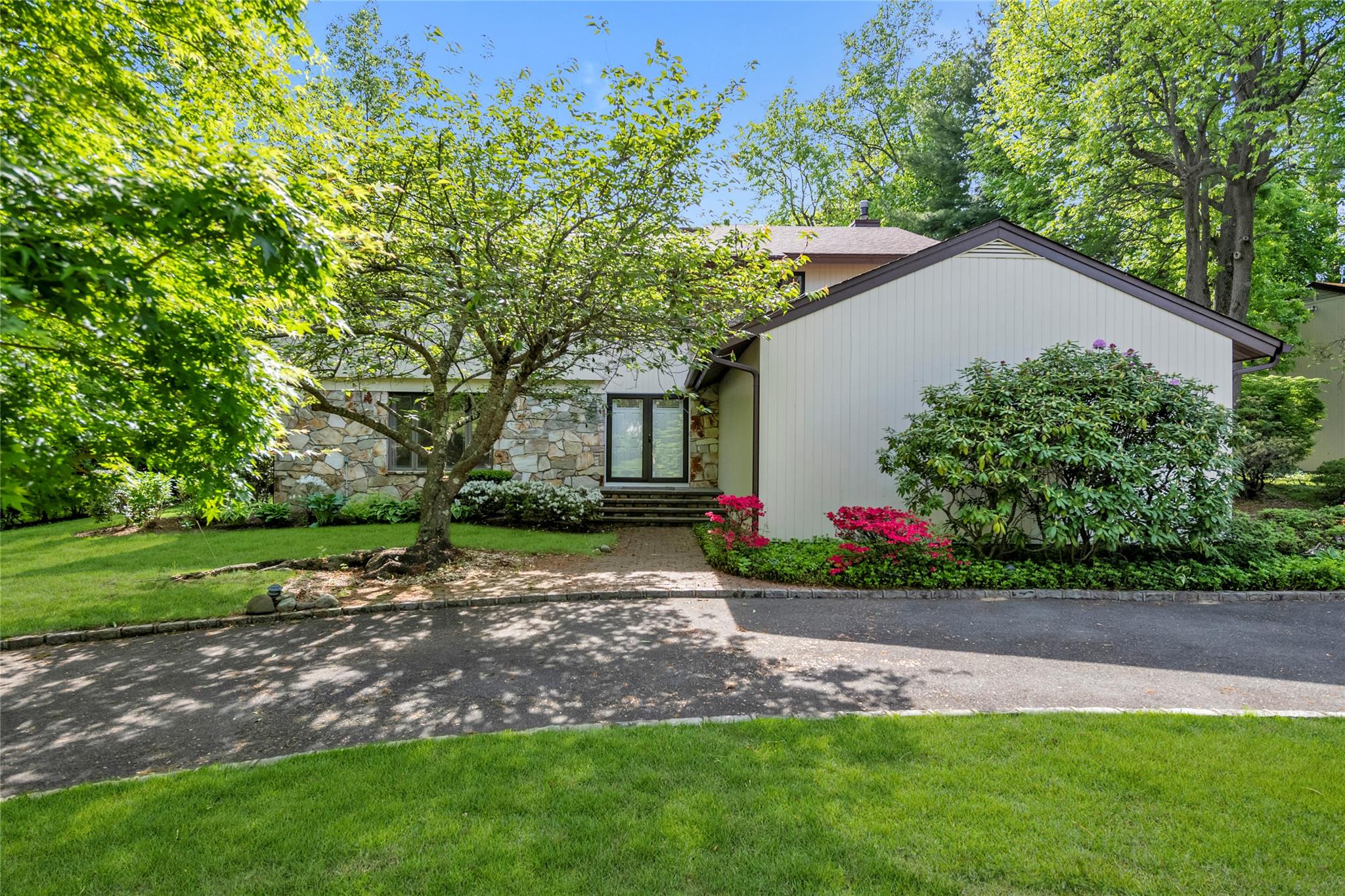 Mid-century home featuring stone siding, a front yard, and a chimney