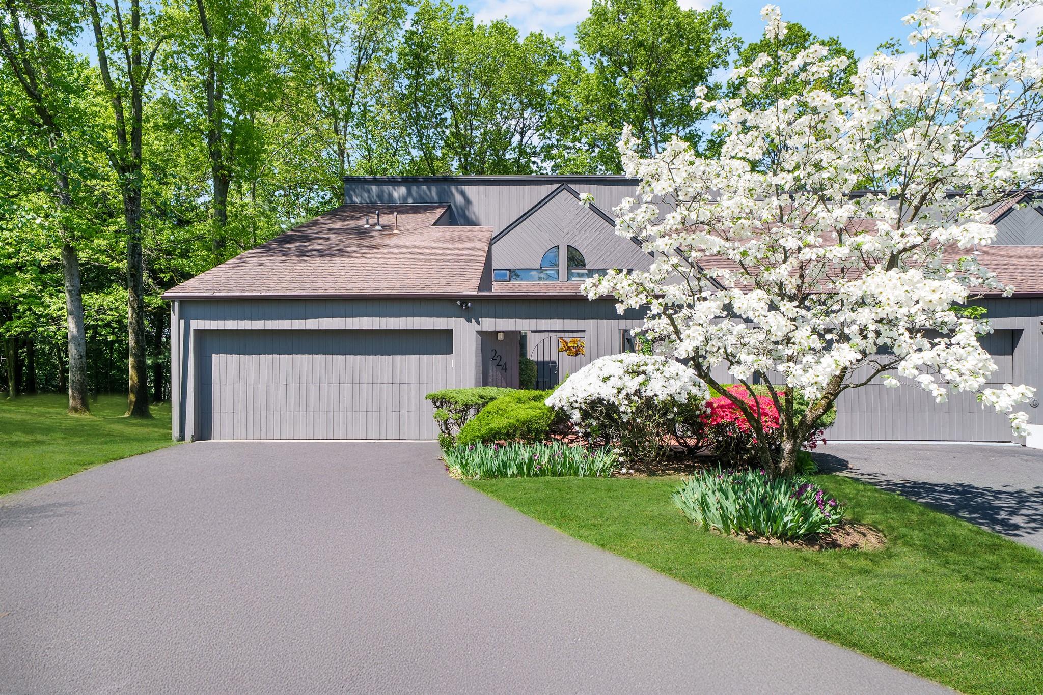 View of front of house featuring driveway, a garage, roof with shingles, and a front lawn