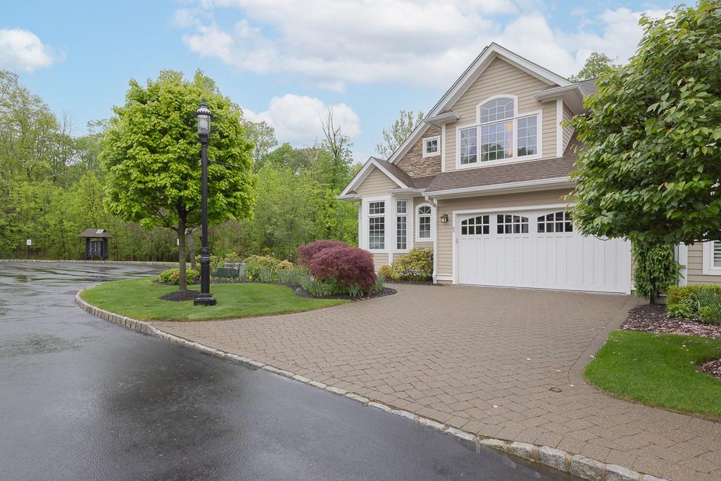 View of front of house featuring decorative driveway, an attached garage, a front yard, and a shingled roof