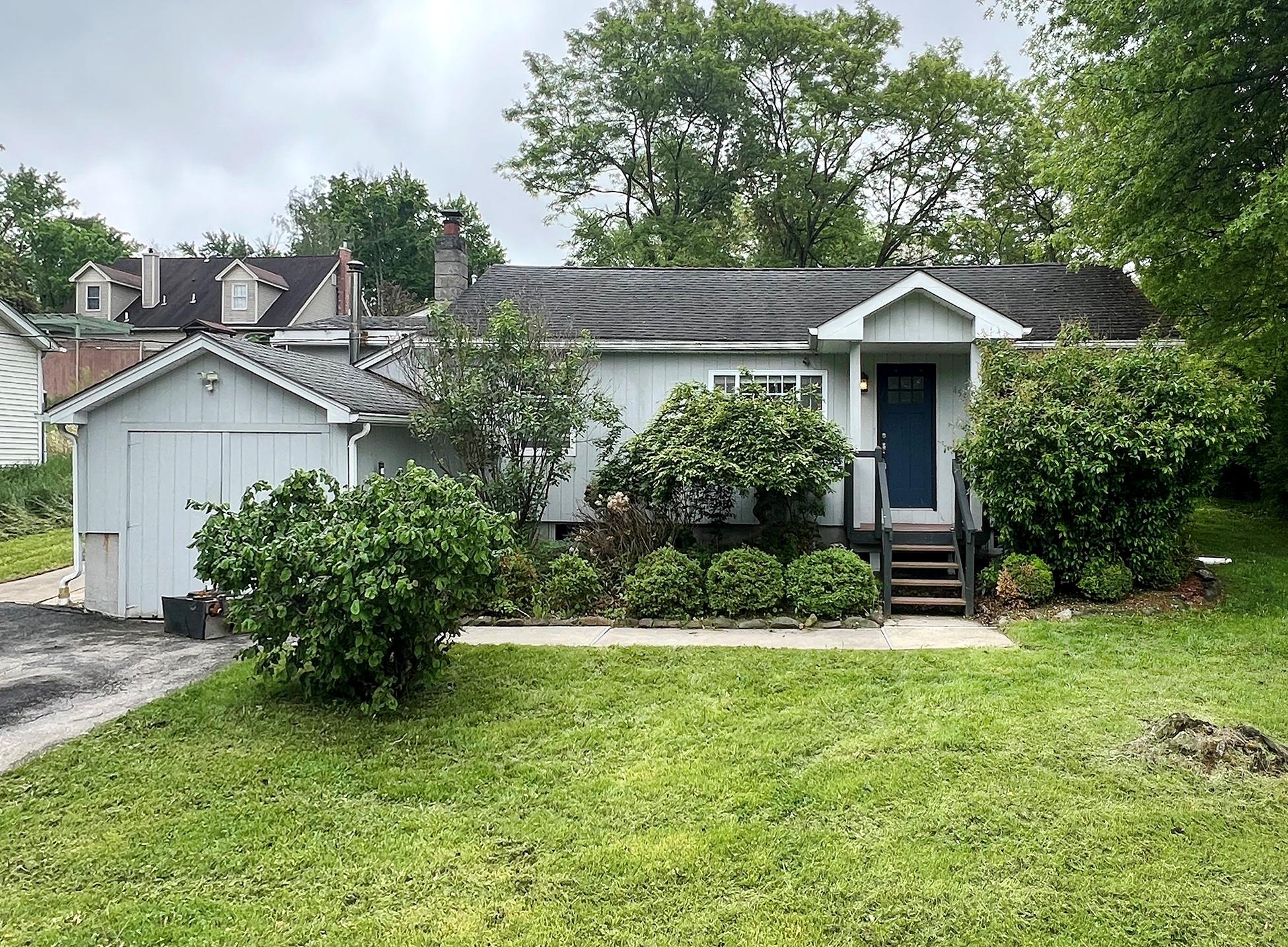 View of front of home with a front lawn, a chimney, and roof with shingles