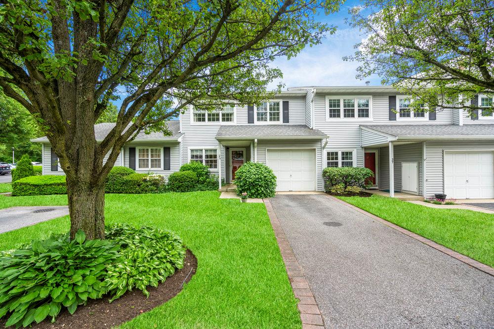 Townhome / multi-family property featuring a front lawn, a garage, and asphalt driveway