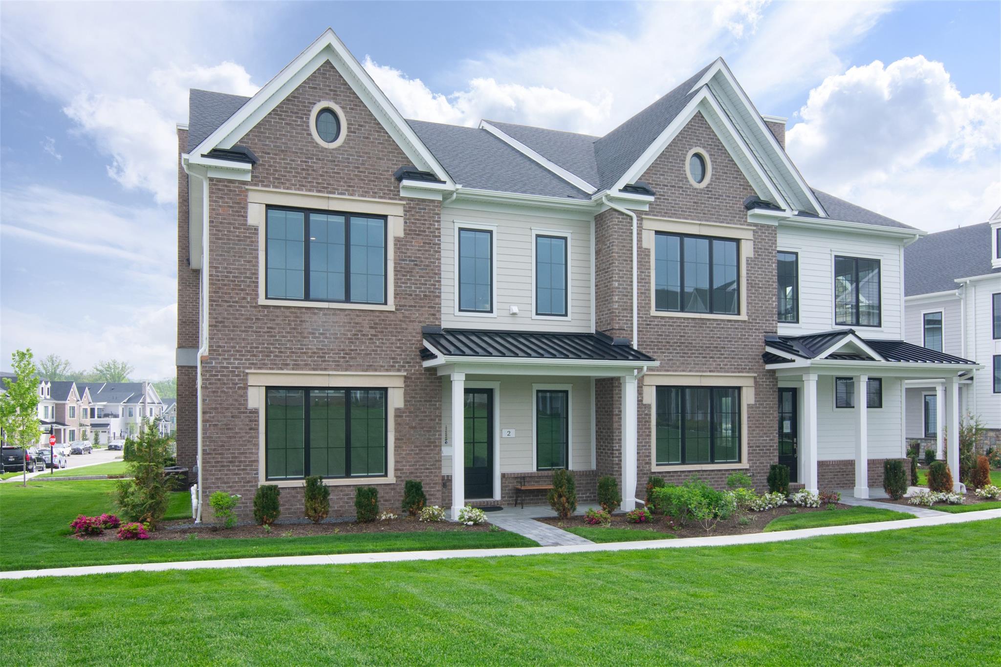 Townhome / multi-family property with brick siding and a front lawn