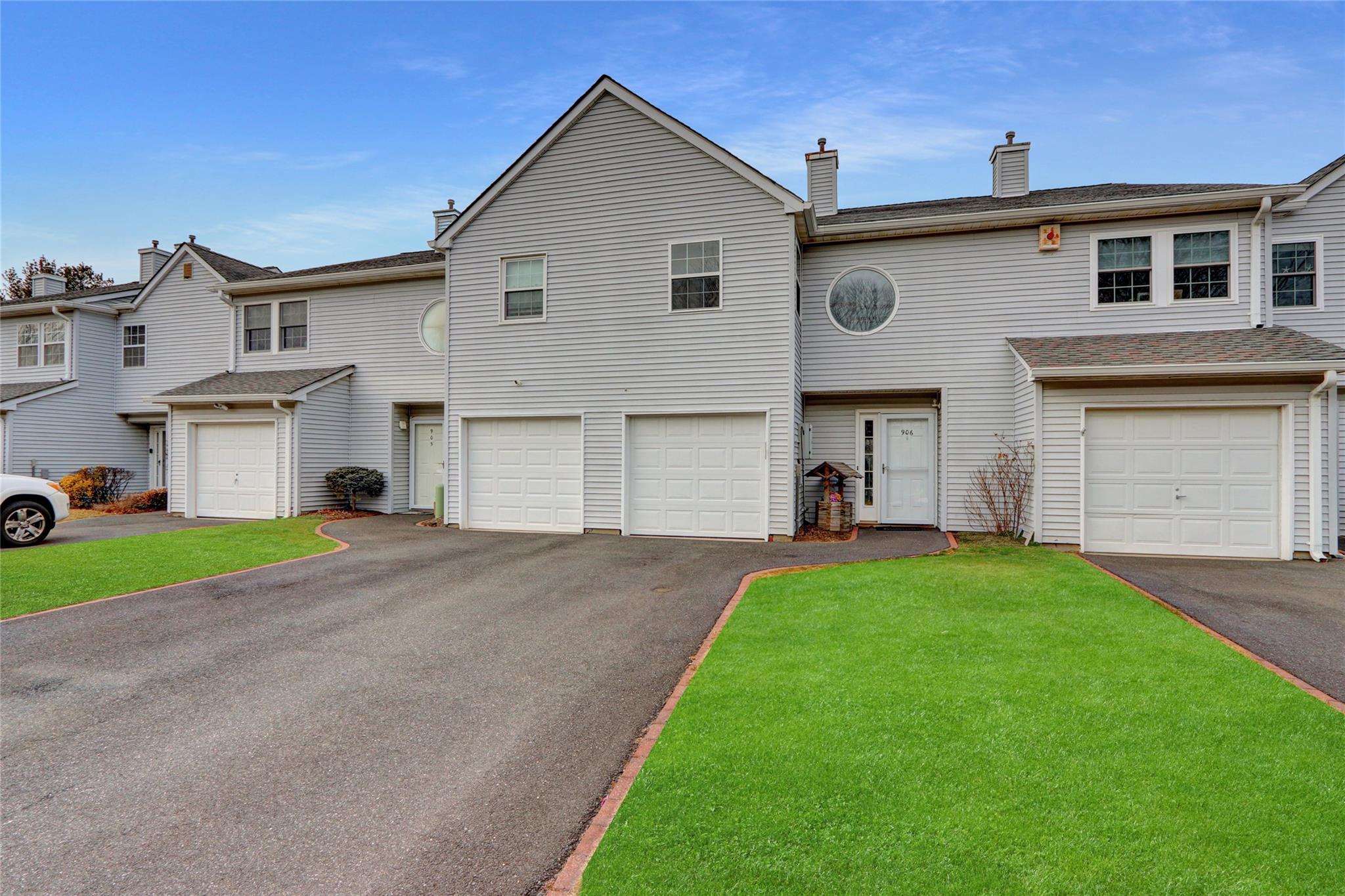 View of property with asphalt driveway, an attached garage, a front lawn, and a chimney