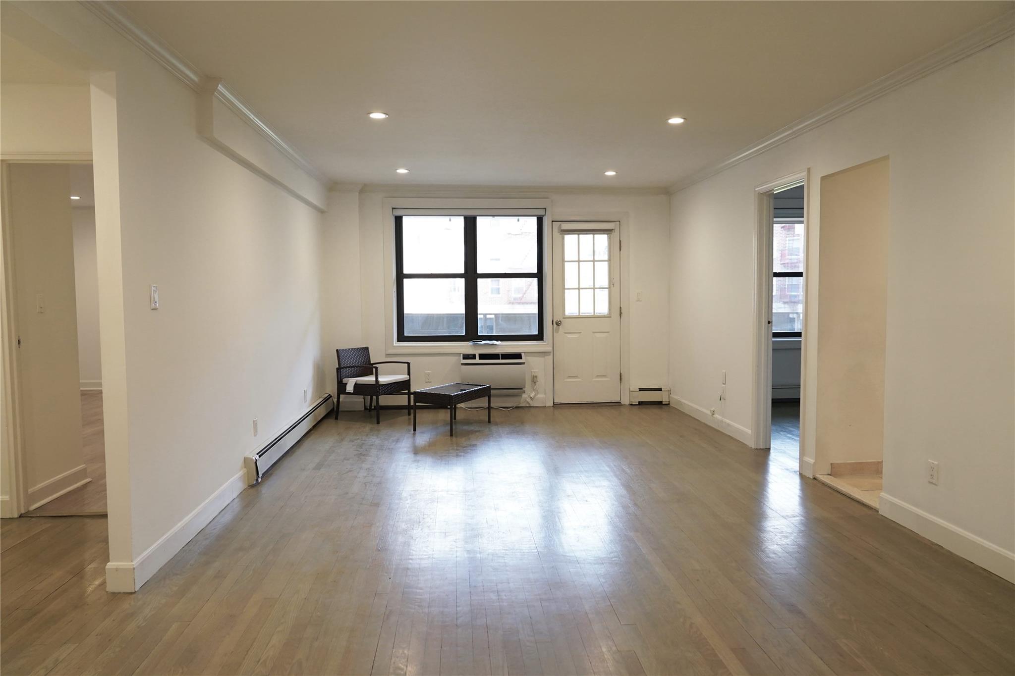 Living room with baseboard heating, crown molding, wood finished floors, baseboards, and recessed lighting