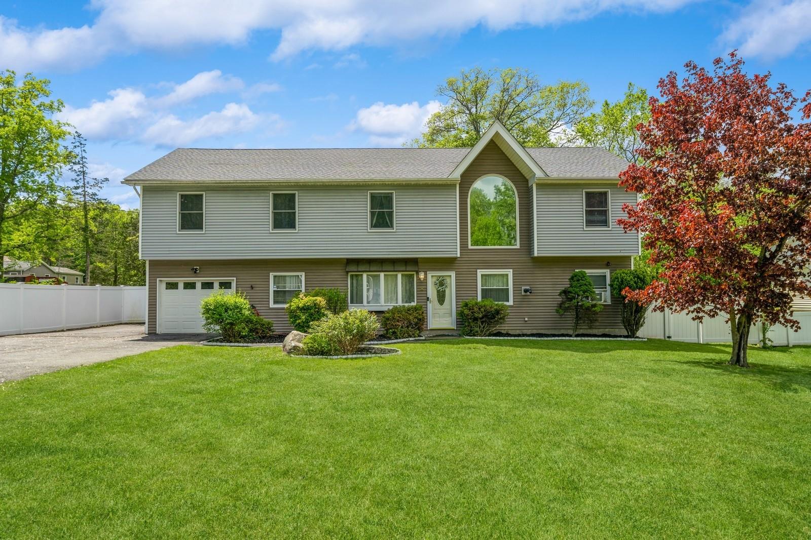 View of front of home featuring asphalt driveway, a garage, and roof with shingles