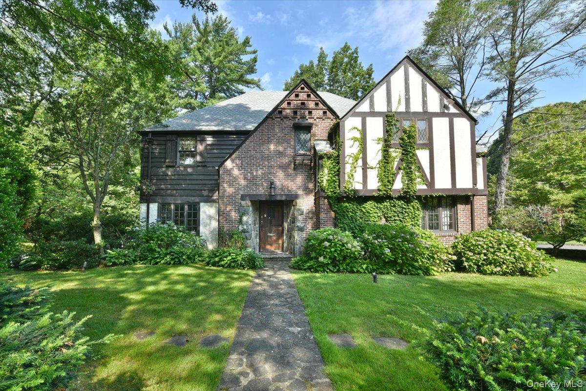 Tudor house featuring brick siding and a front yard