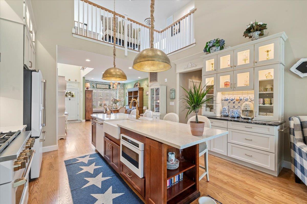 Kitchen featuring stainless steel appliances, light wood-type flooring, white cabinets, a sink, and a kitchen breakfast bar