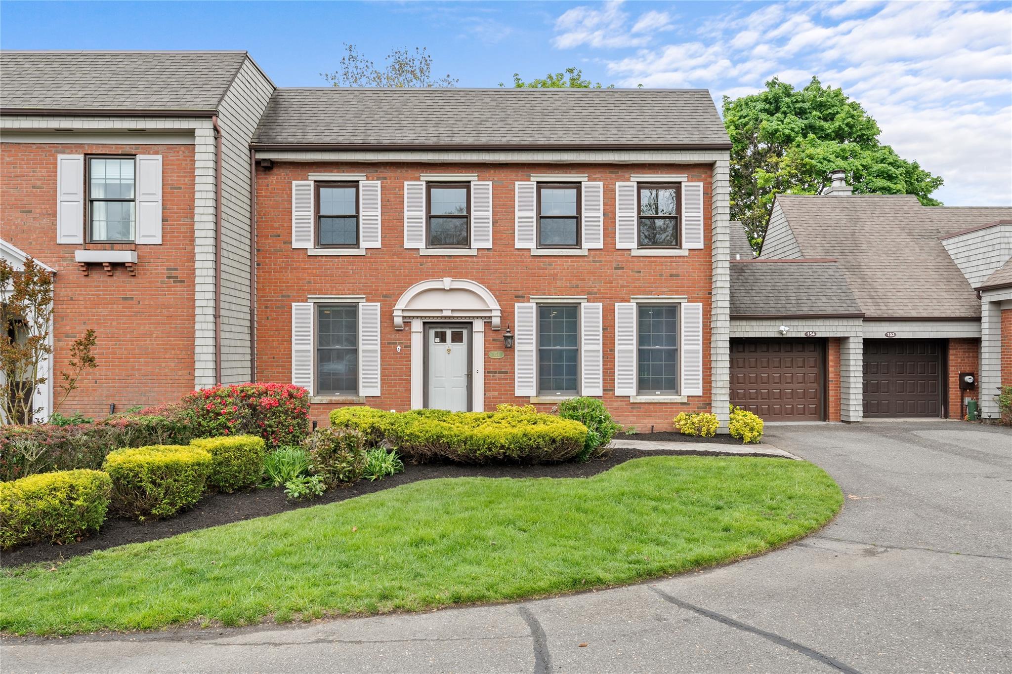 View of front of home featuring a garage, asphalt driveway, brick siding, and a front lawn