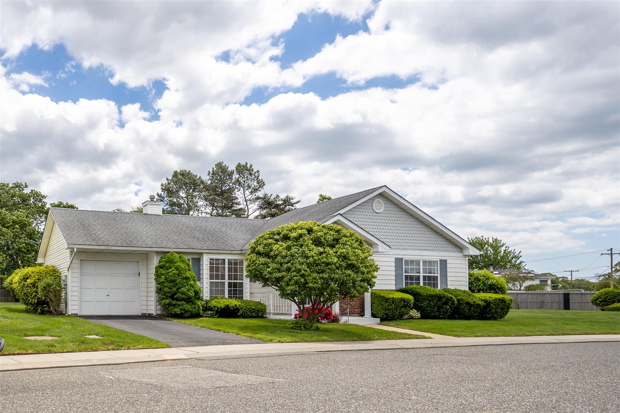 View of front of property featuring an attached garage, asphalt driveway, a chimney, and roof with shingles
