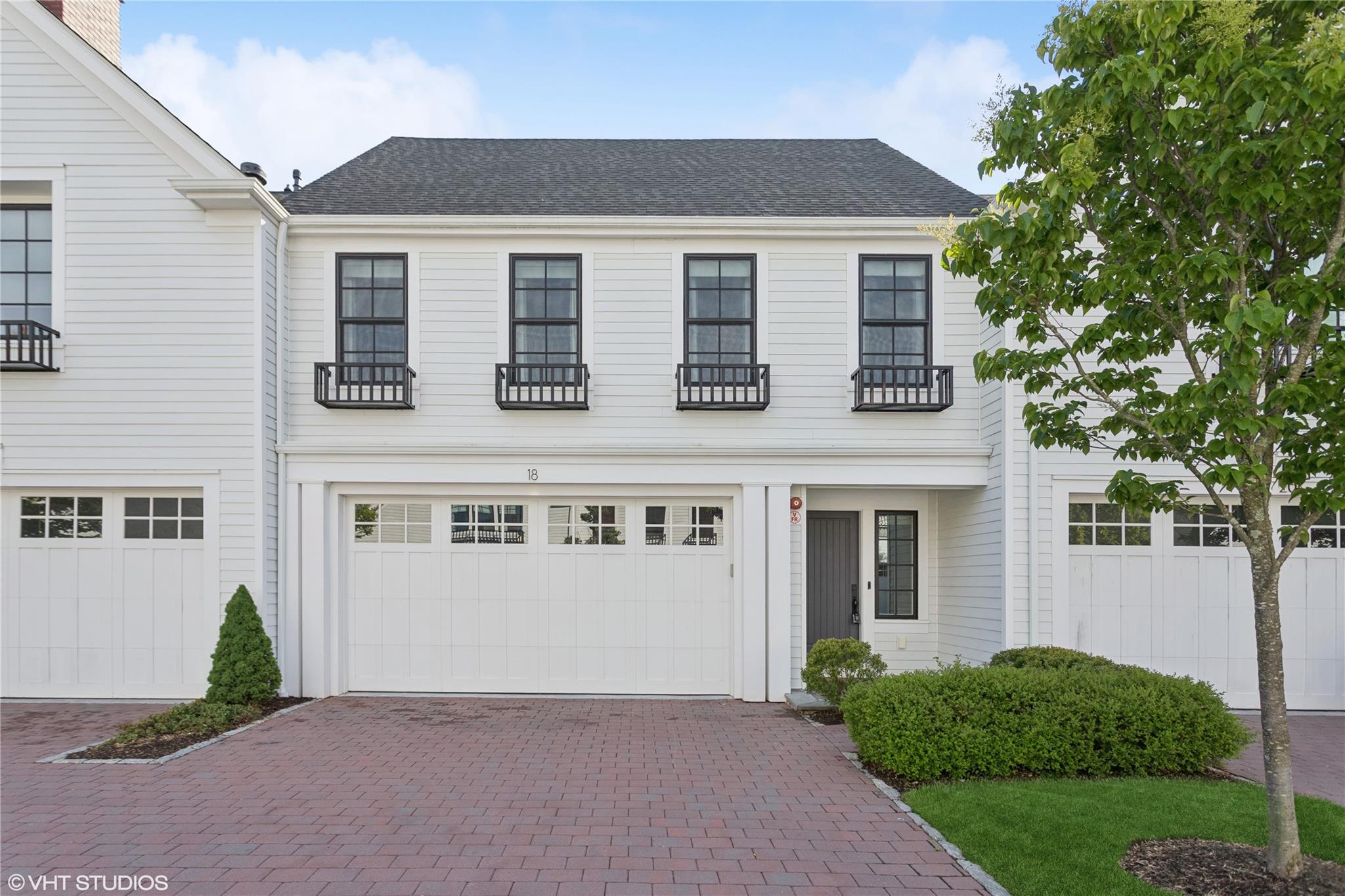 View of front of home featuring decorative driveway, a garage, and a shingled roof