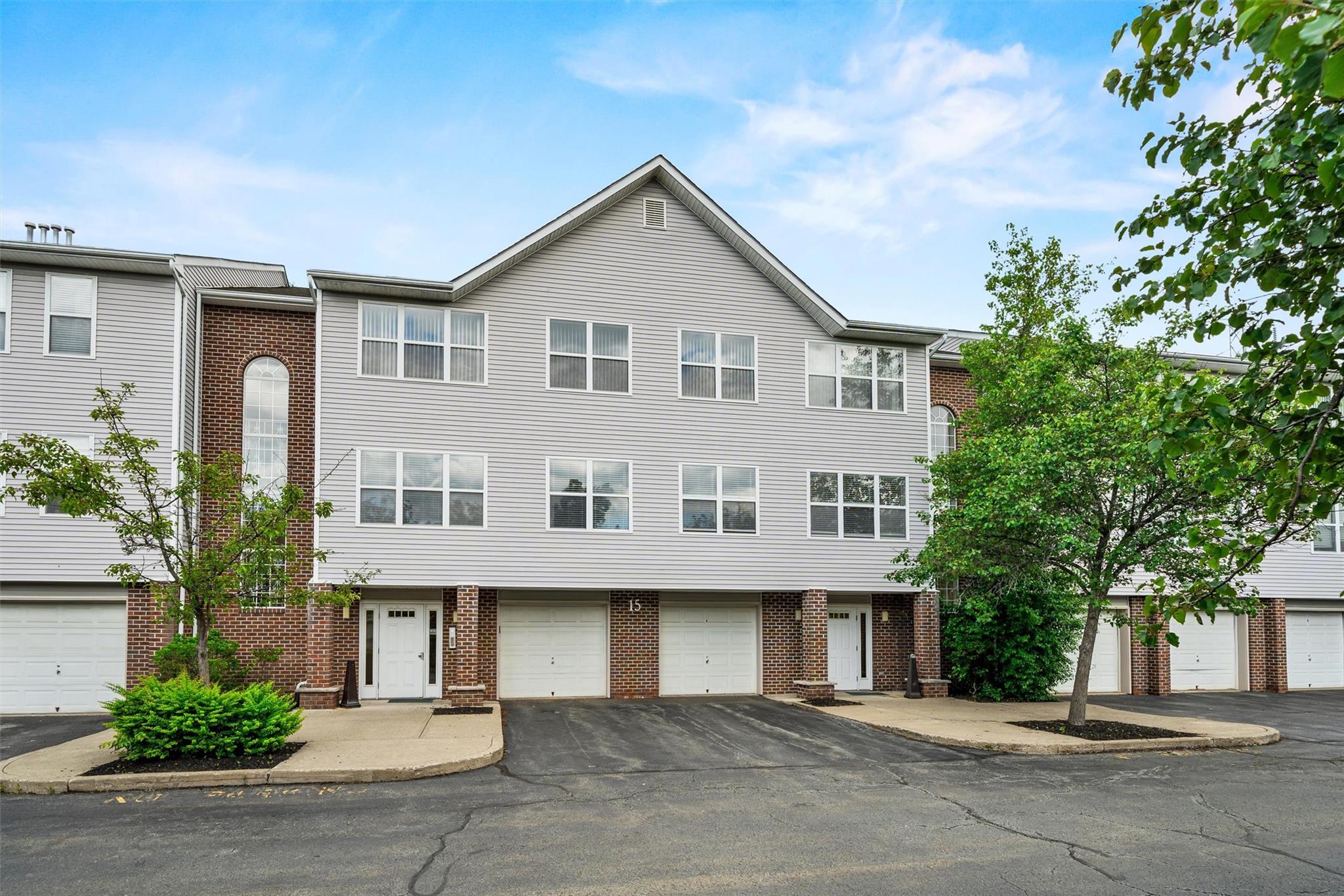 View of property featuring brick siding, driveway, and a garage