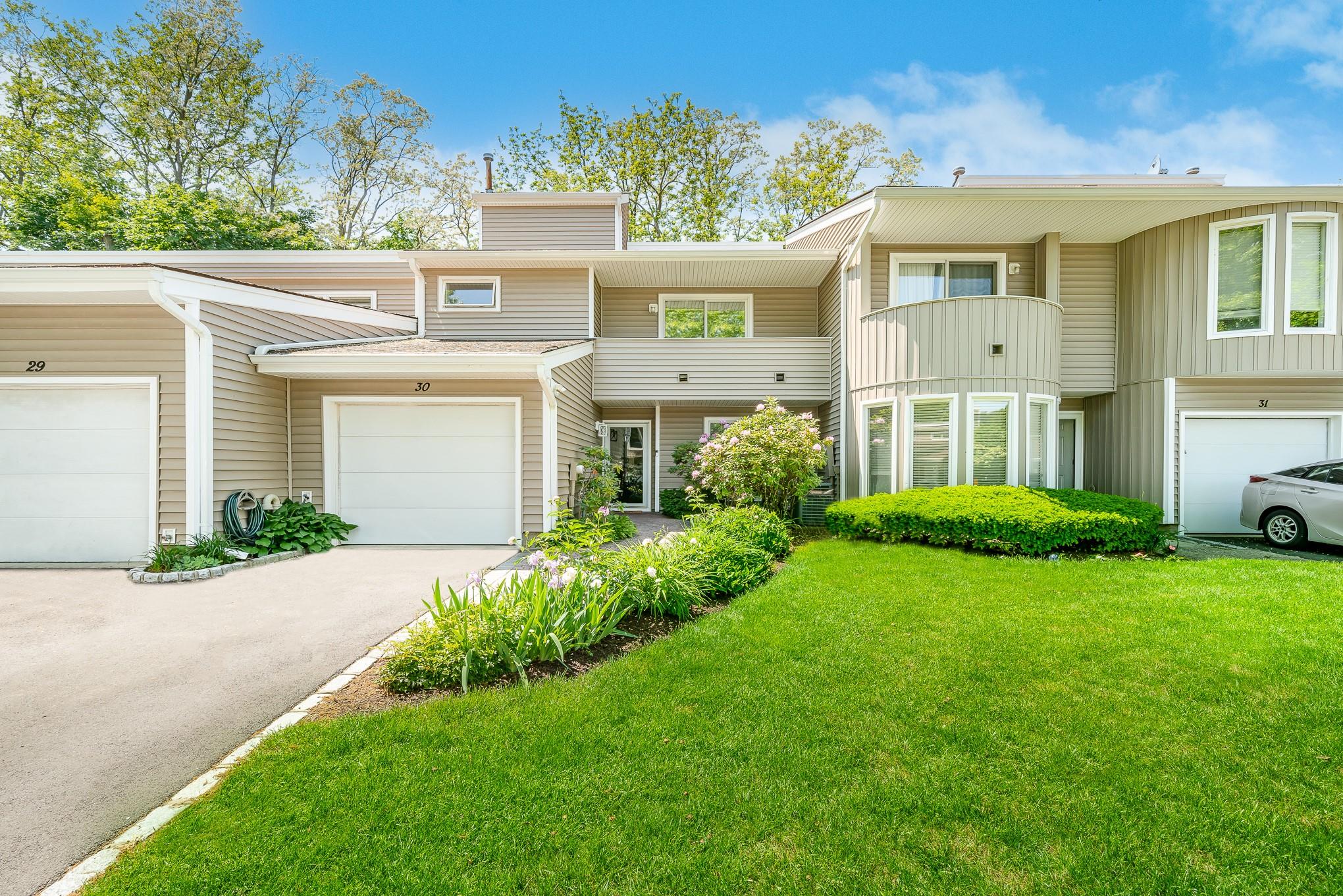 Multi unit property with a front lawn, driveway, a garage, and board and batten siding