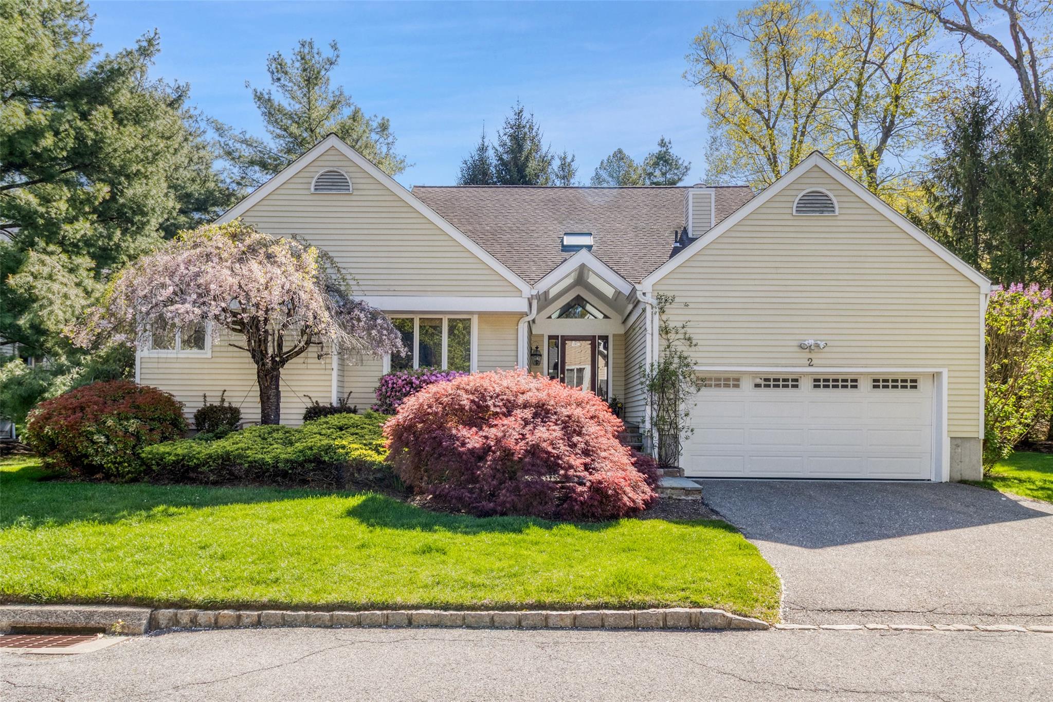View of front of home with driveway, a front lawn, a garage, and a chimney