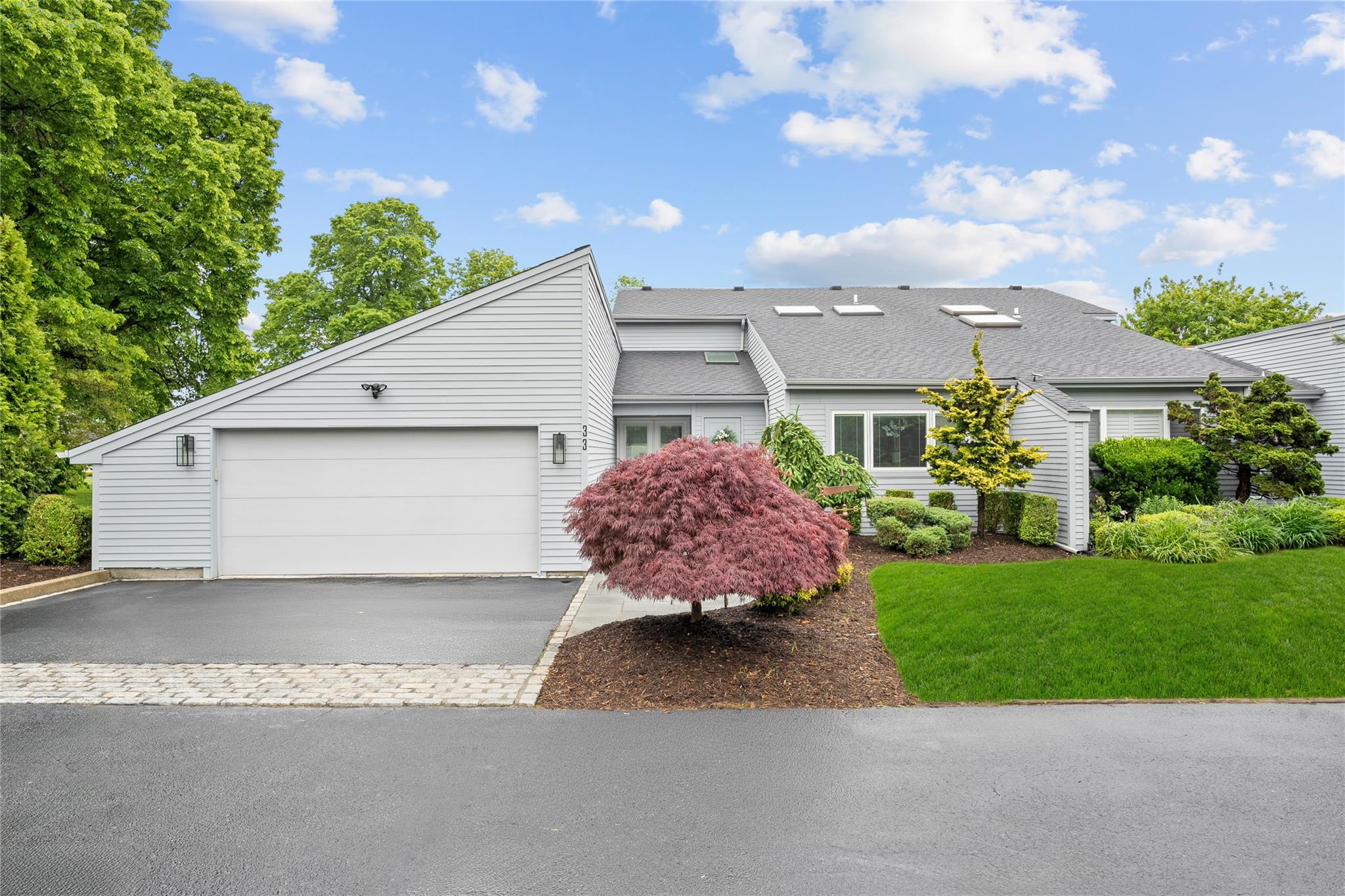 View of front of property with asphalt driveway, a garage, a shingled roof, and a front lawn