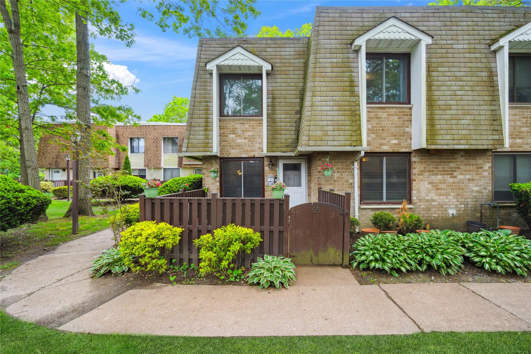 View of property featuring mansard roof, a gate, and brick siding