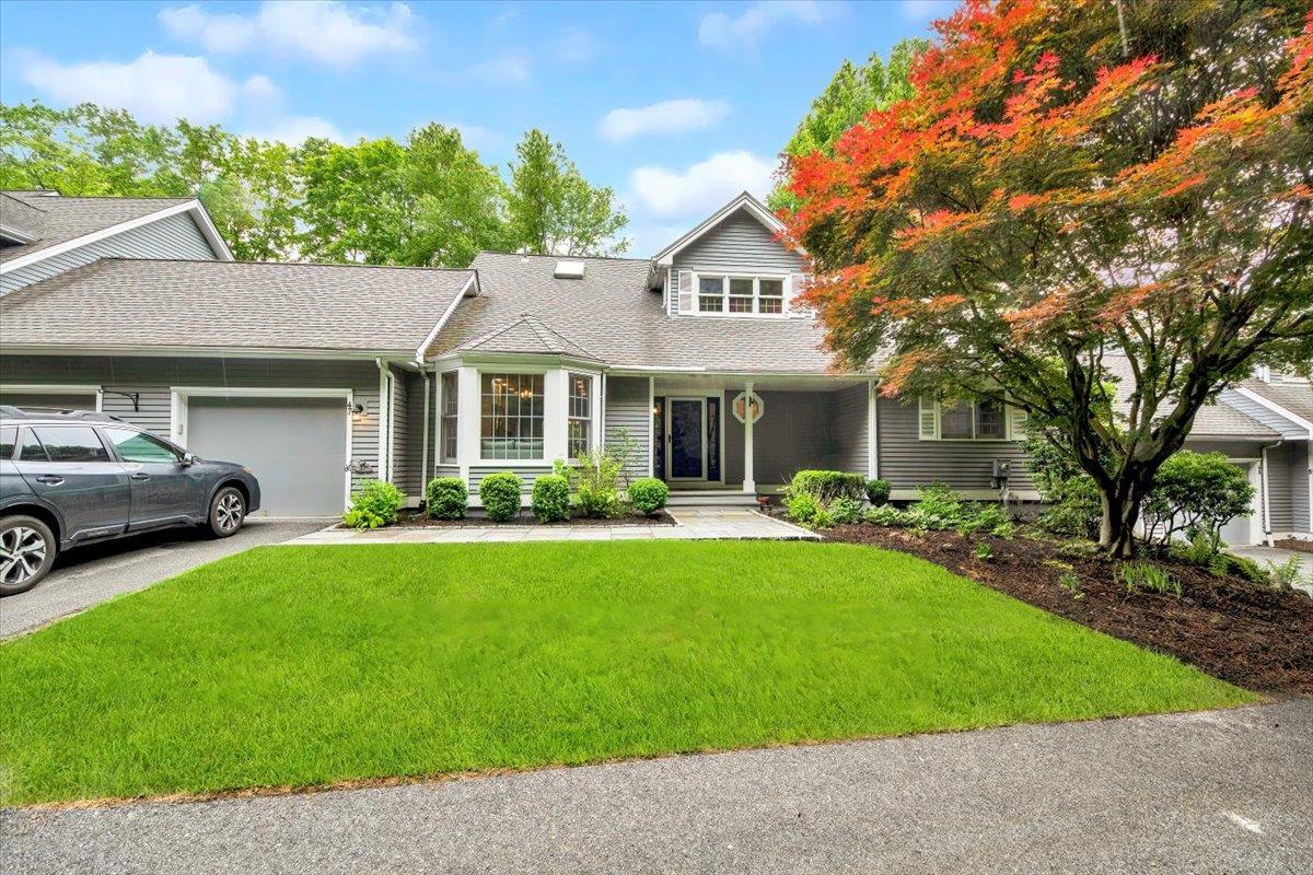 View of front of house with a garage, concrete driveway, a front lawn, and a shingled roof