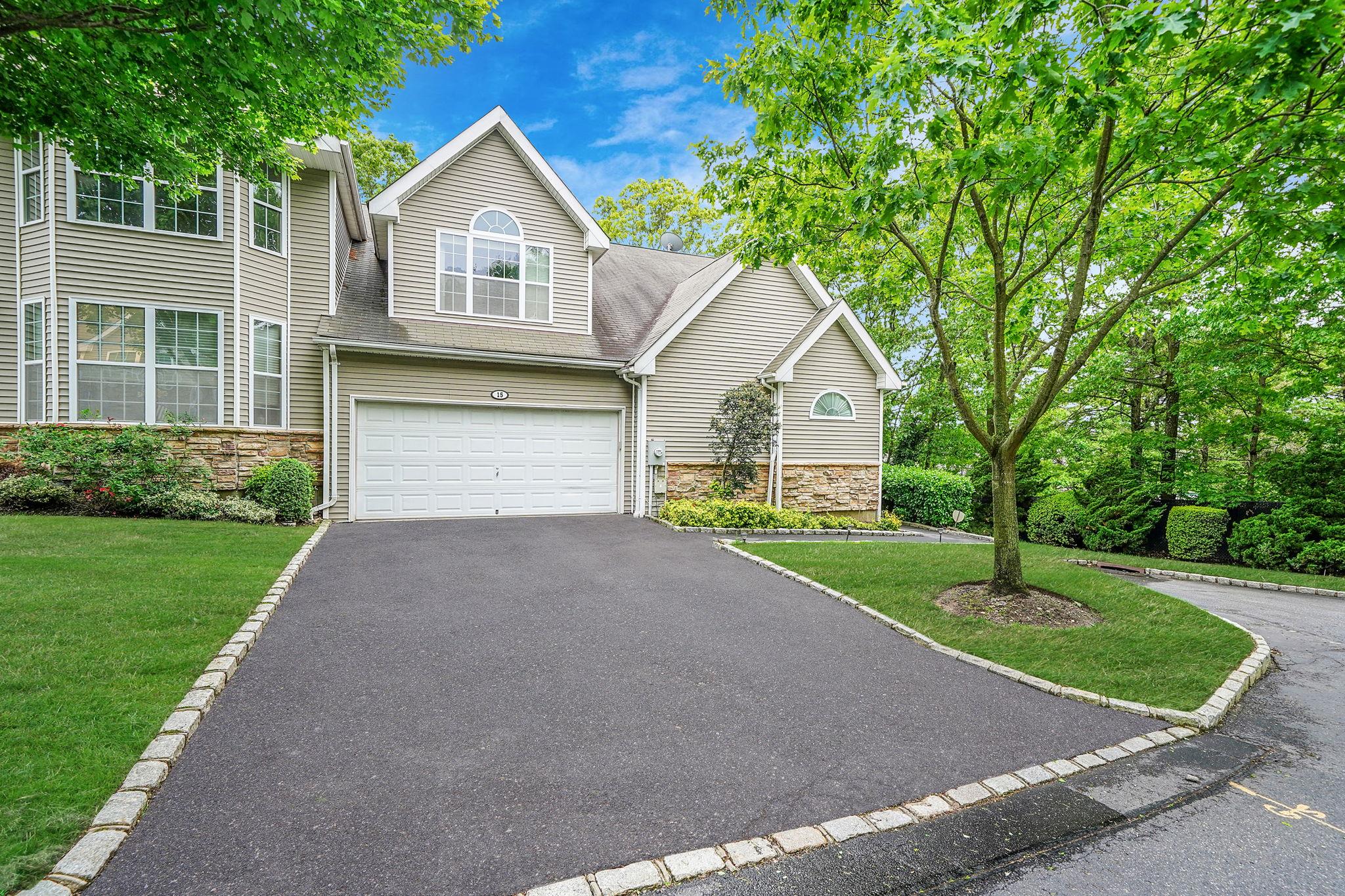 Traditional home with stone siding, driveway, a front lawn, and a garage