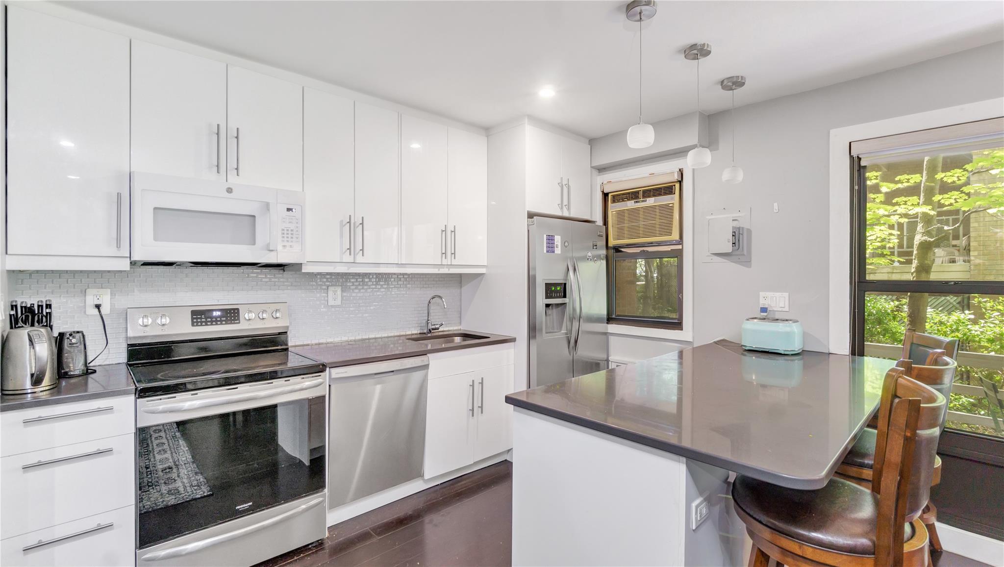 Kitchen with appliances with stainless steel finishes, a sink, white cabinets, decorative backsplash, and recessed lighting
