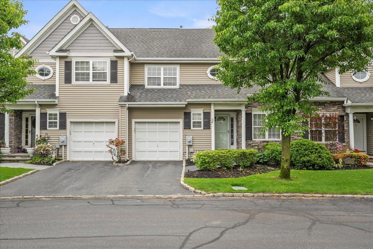 View of front of property featuring driveway, roof with shingles, and an attached garage