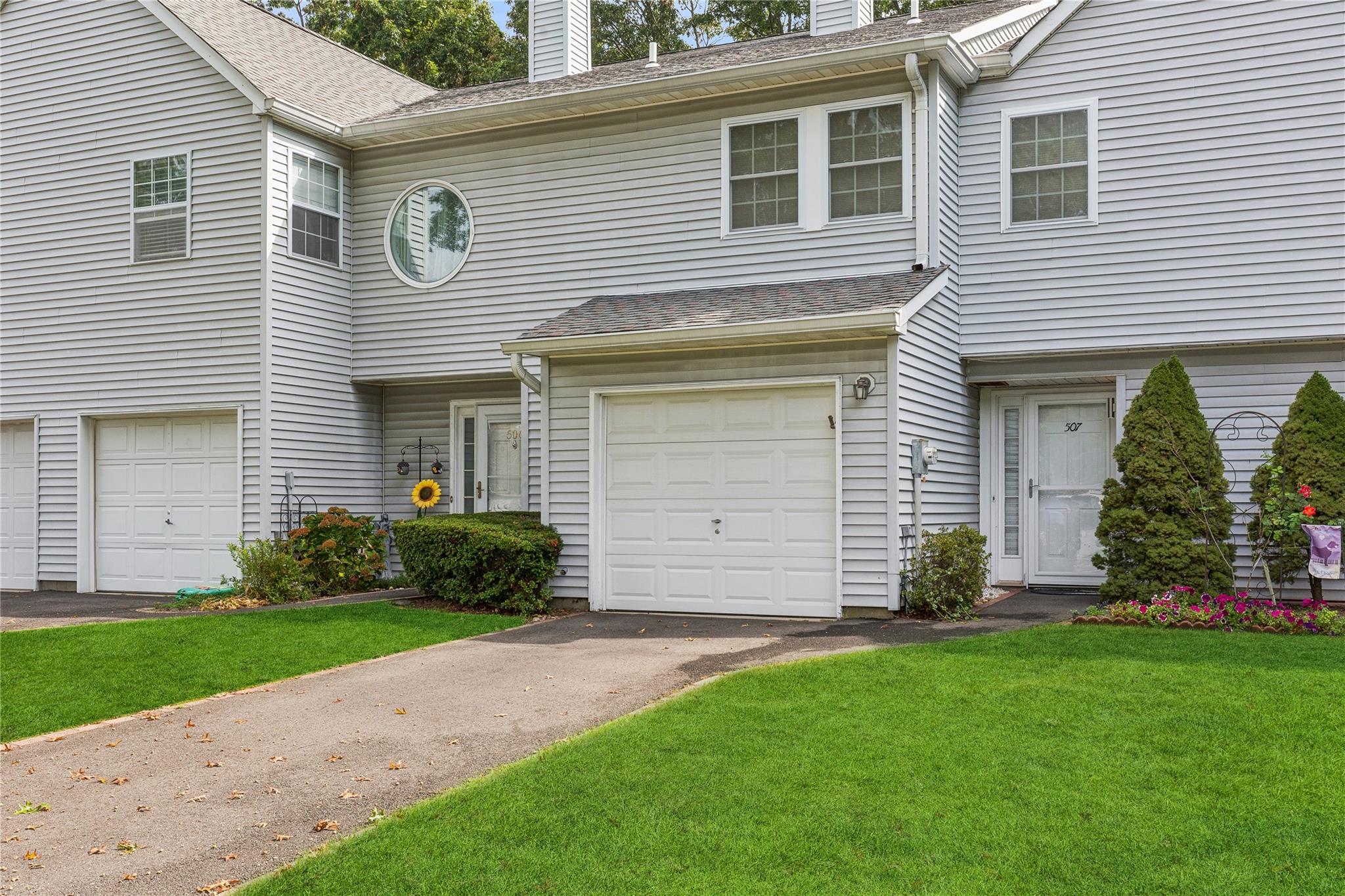 View of property featuring a chimney, a garage, and a front yard