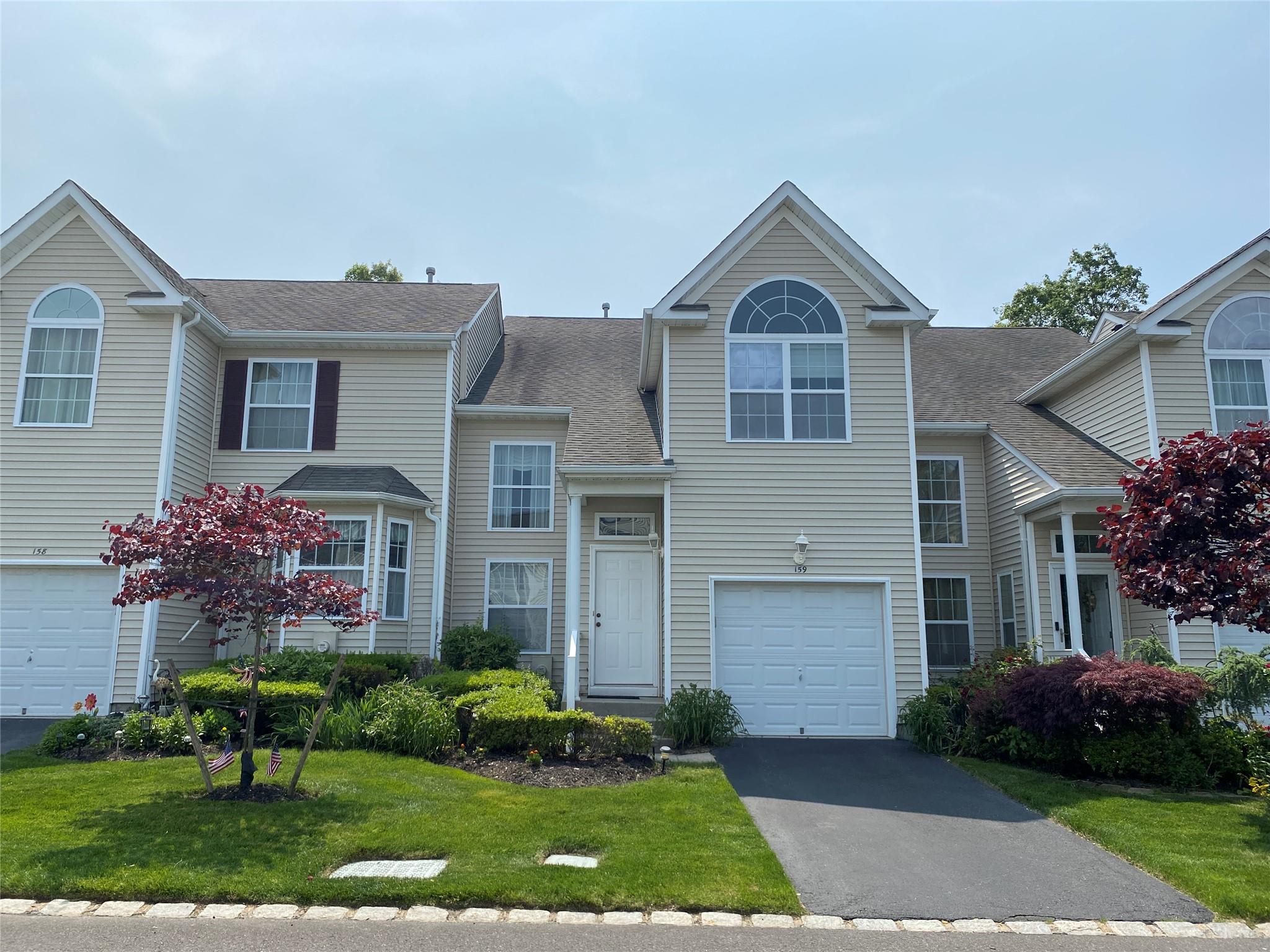 View of front of house with driveway, a shingled roof, a front lawn, and a garage