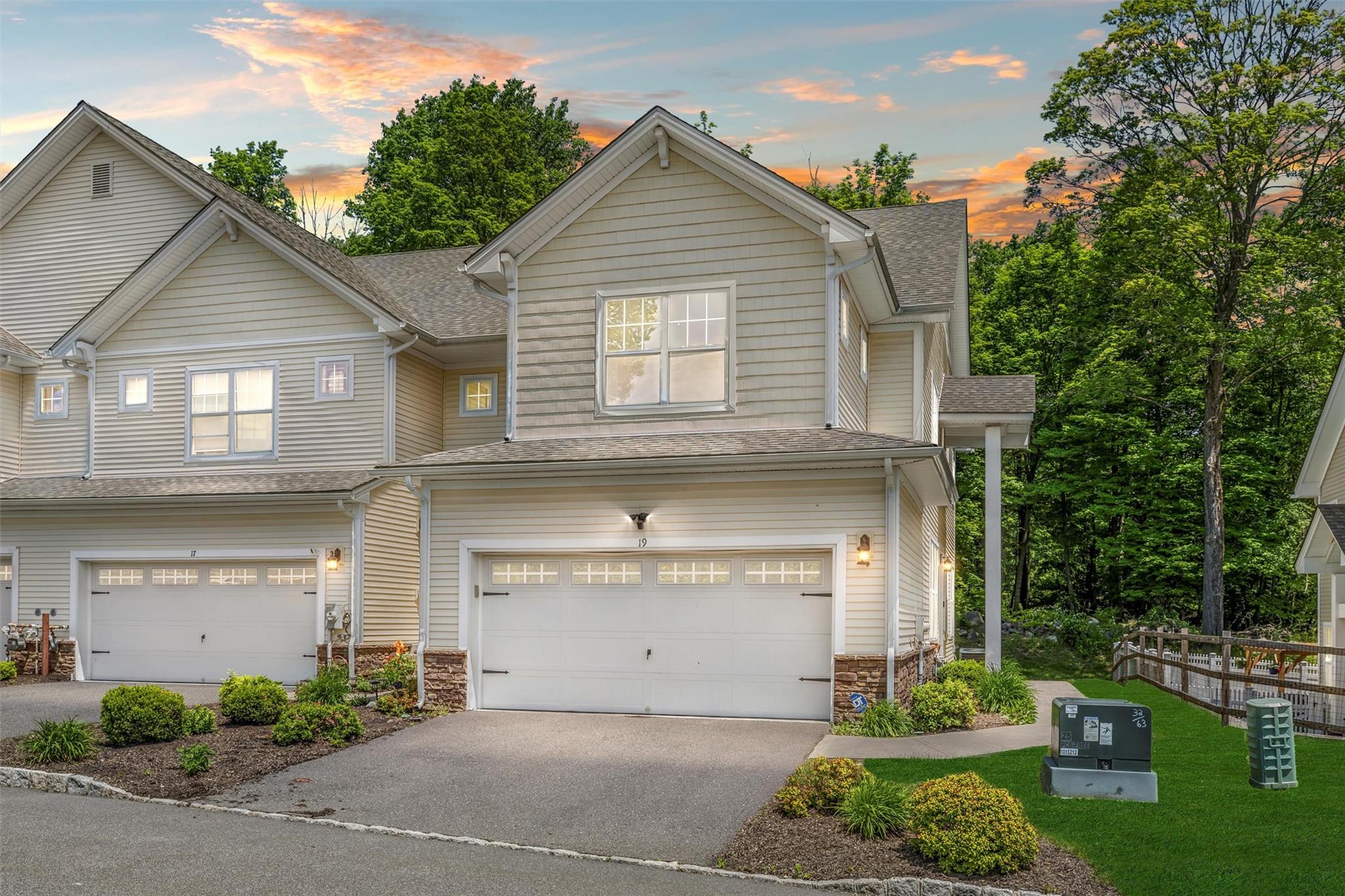 View of front of property with an attached garage, driveway, a shingled roof, and stone siding