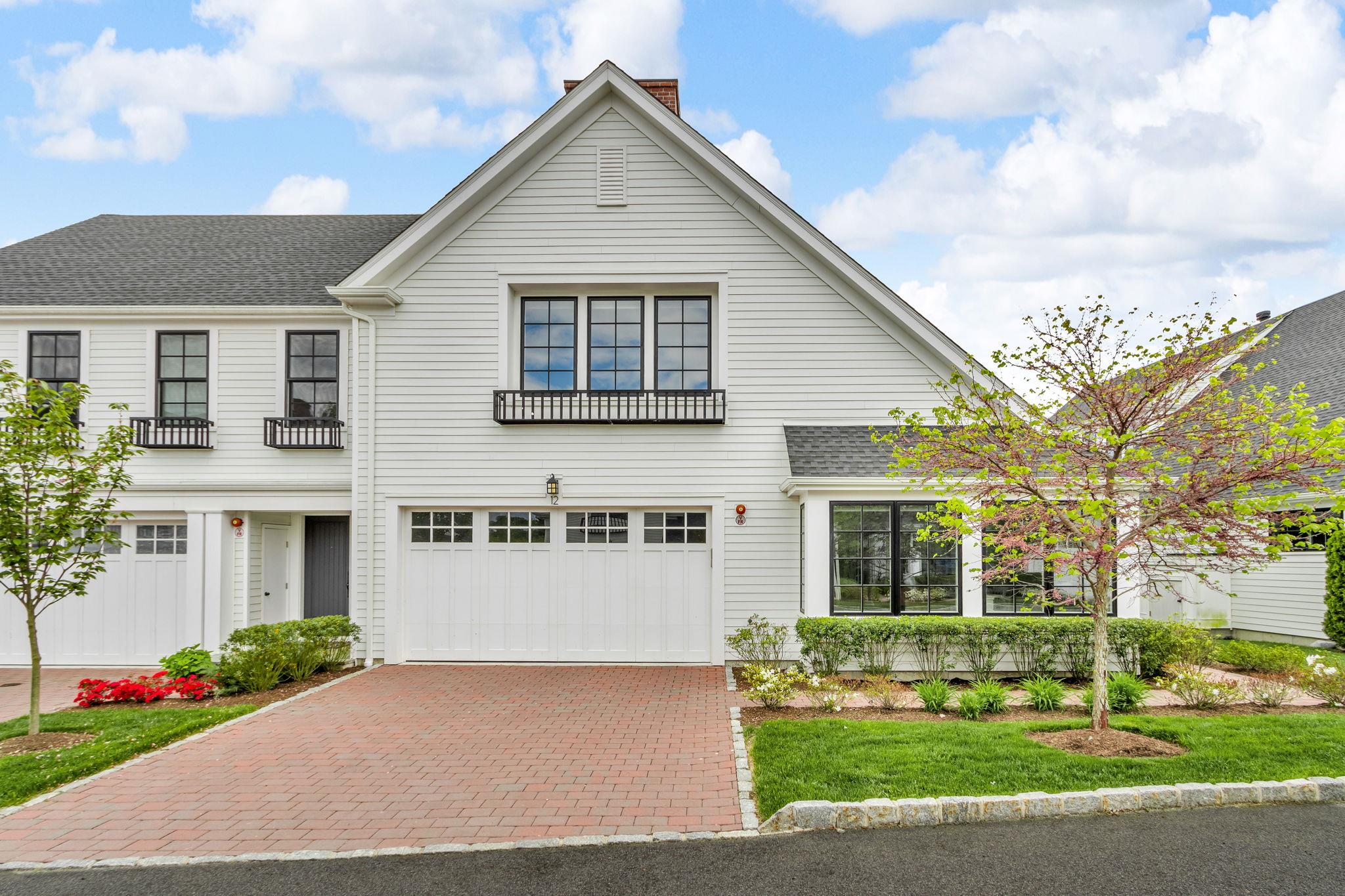 View of front of property featuring a chimney, decorative driveway, an attached garage, and a shingled roof