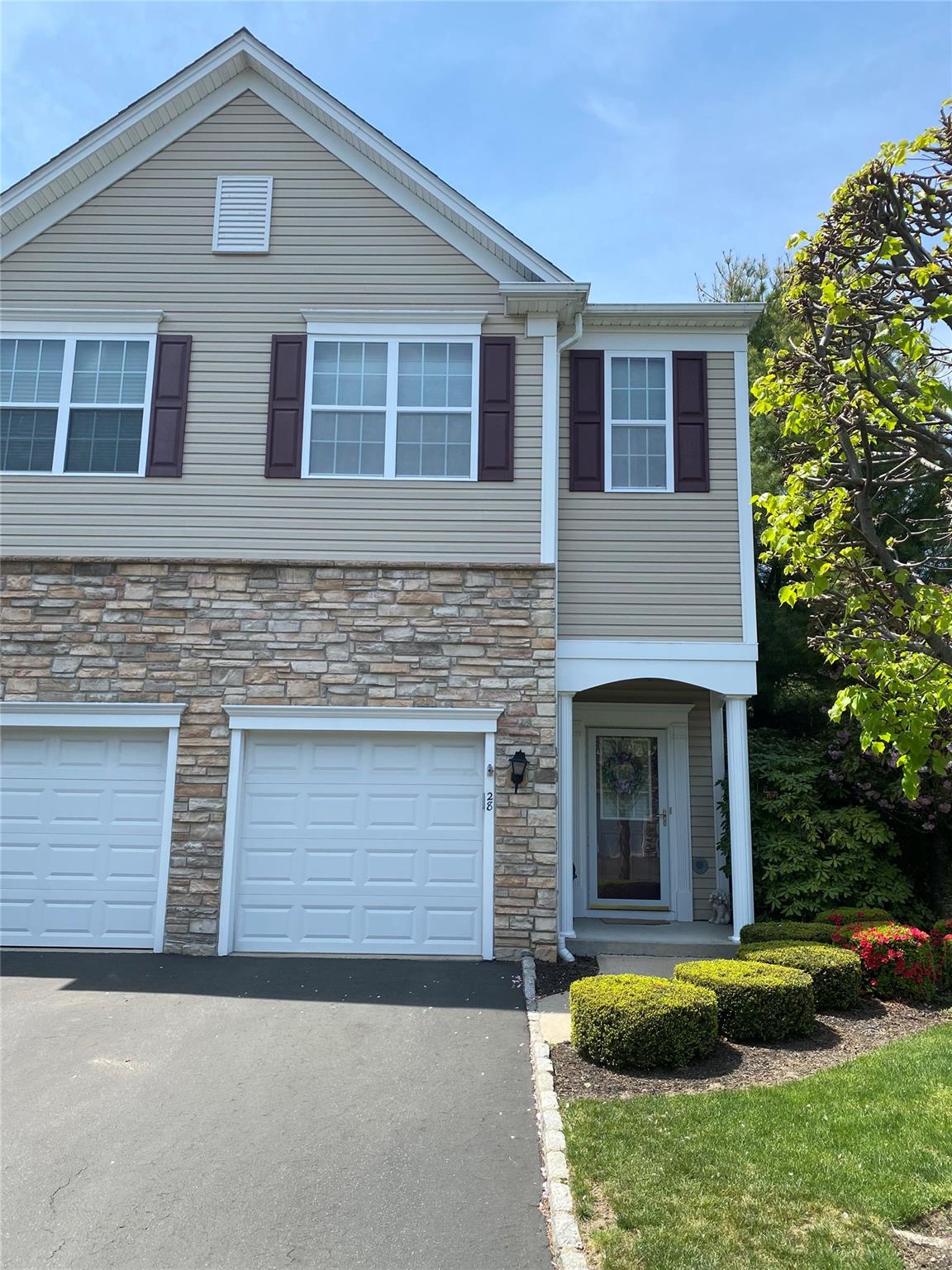 Townhome / multi-family property featuring stone siding, driveway, and a garage