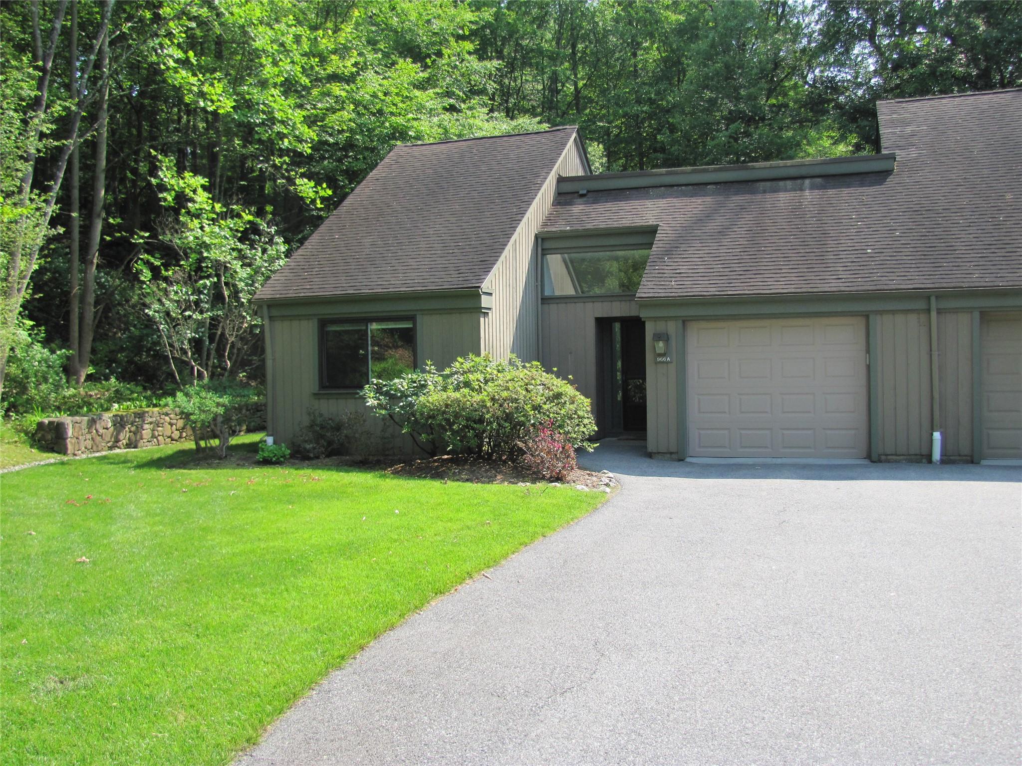 View of front of property featuring a shingled roof, driveway, an attached garage, and a front yard
