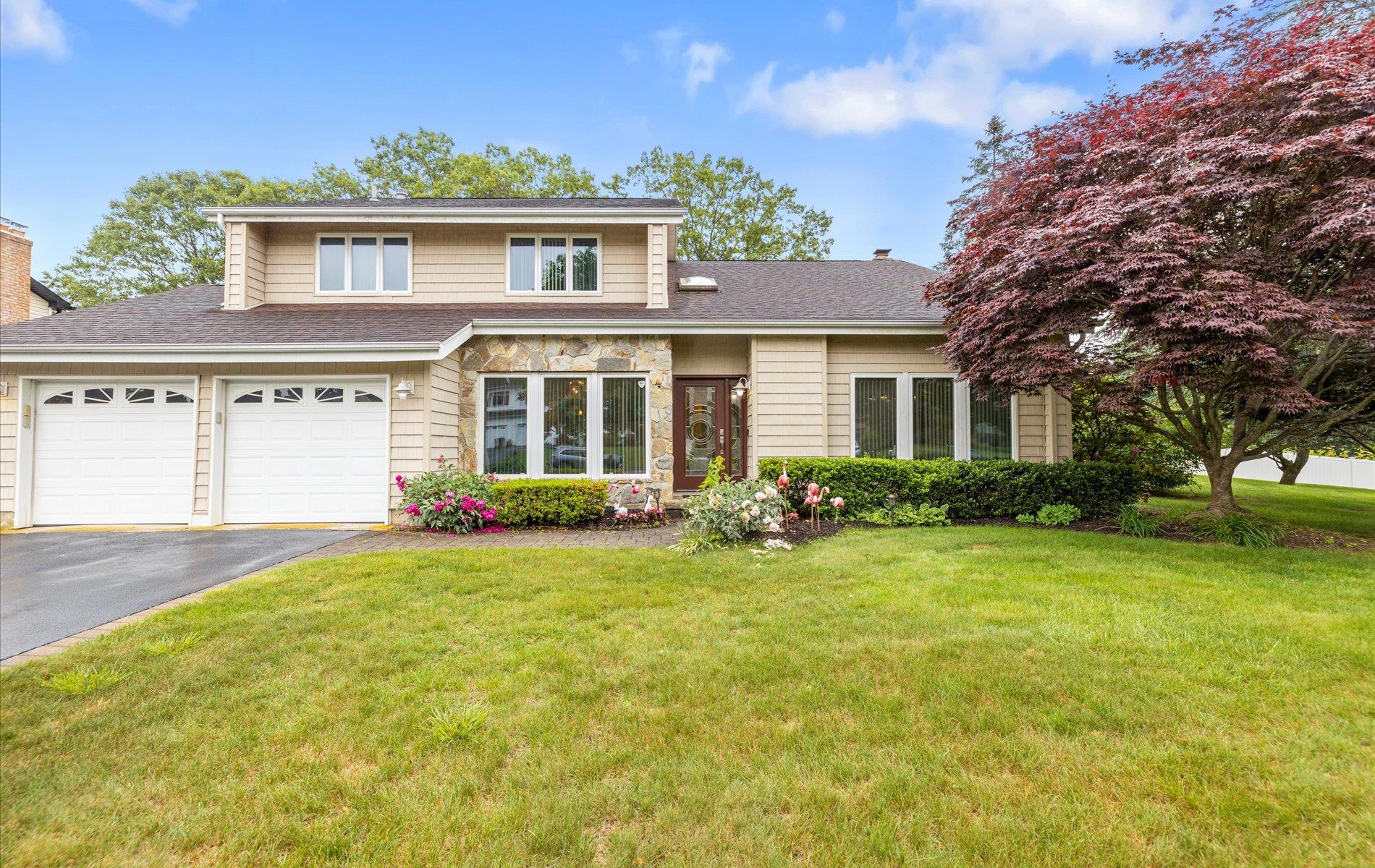View of front facade with driveway, a front lawn, a shingled roof, and a garage