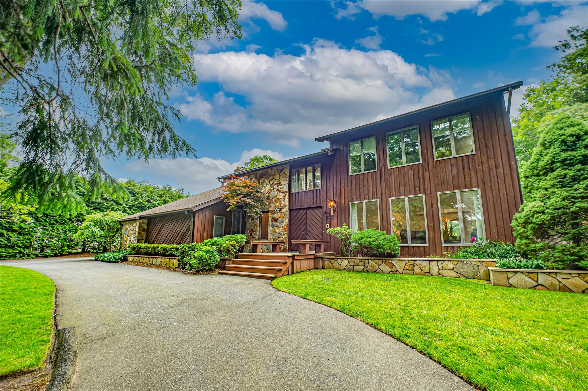 View of front of home featuring asphalt driveway and a front yard
