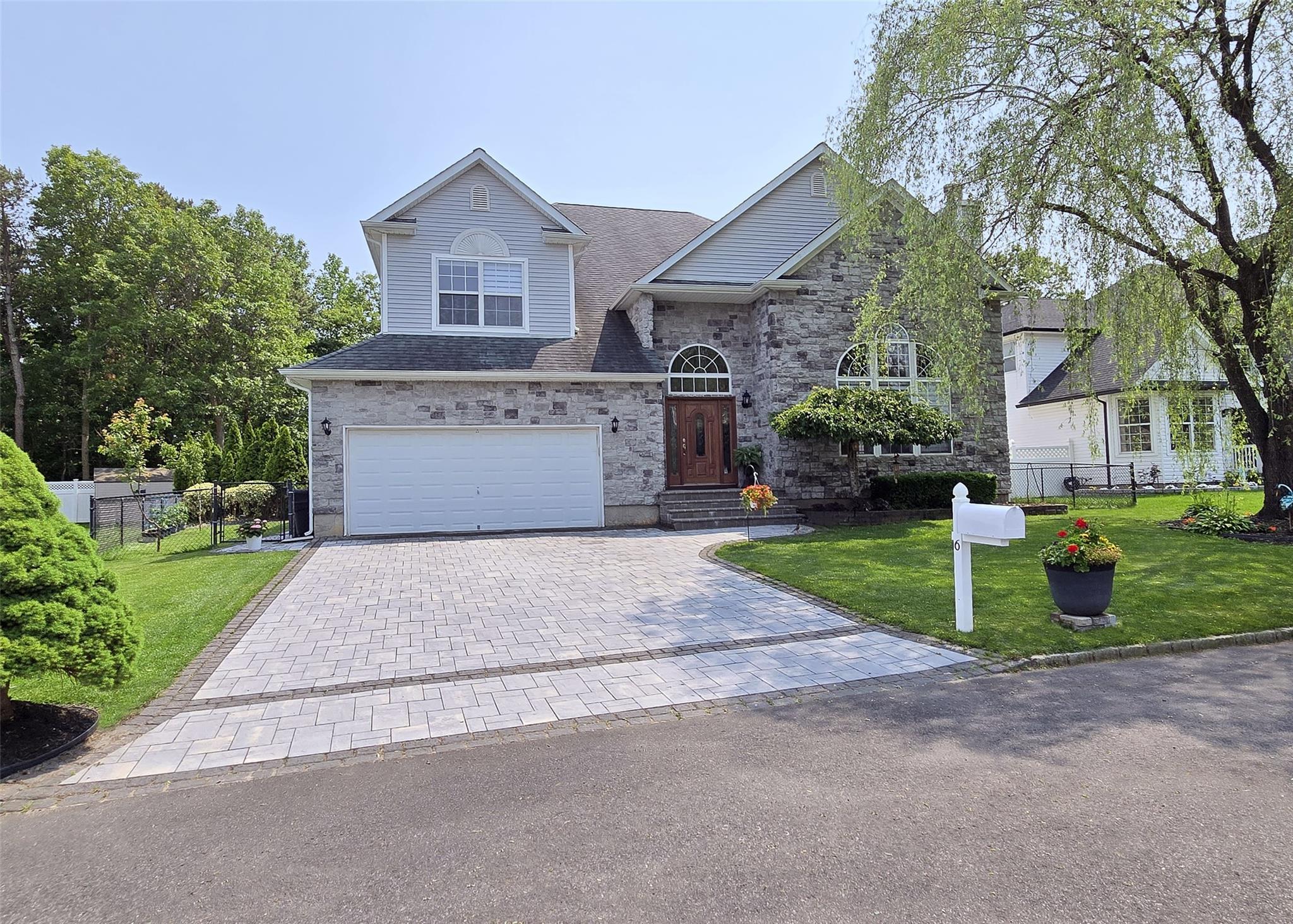 Traditional home with stone paved driveway, a garage, and stone siding