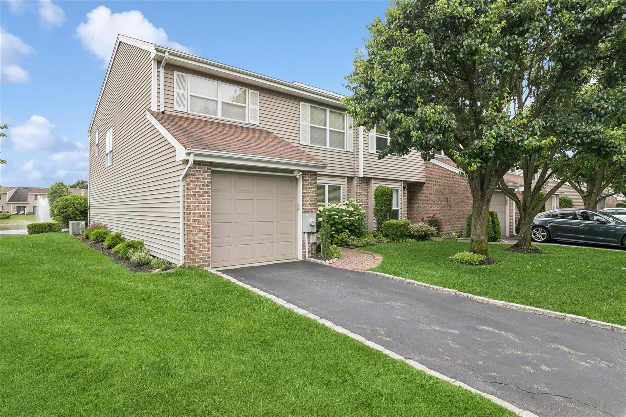 View of front of house featuring brick siding, asphalt driveway, a garage, and a front lawn