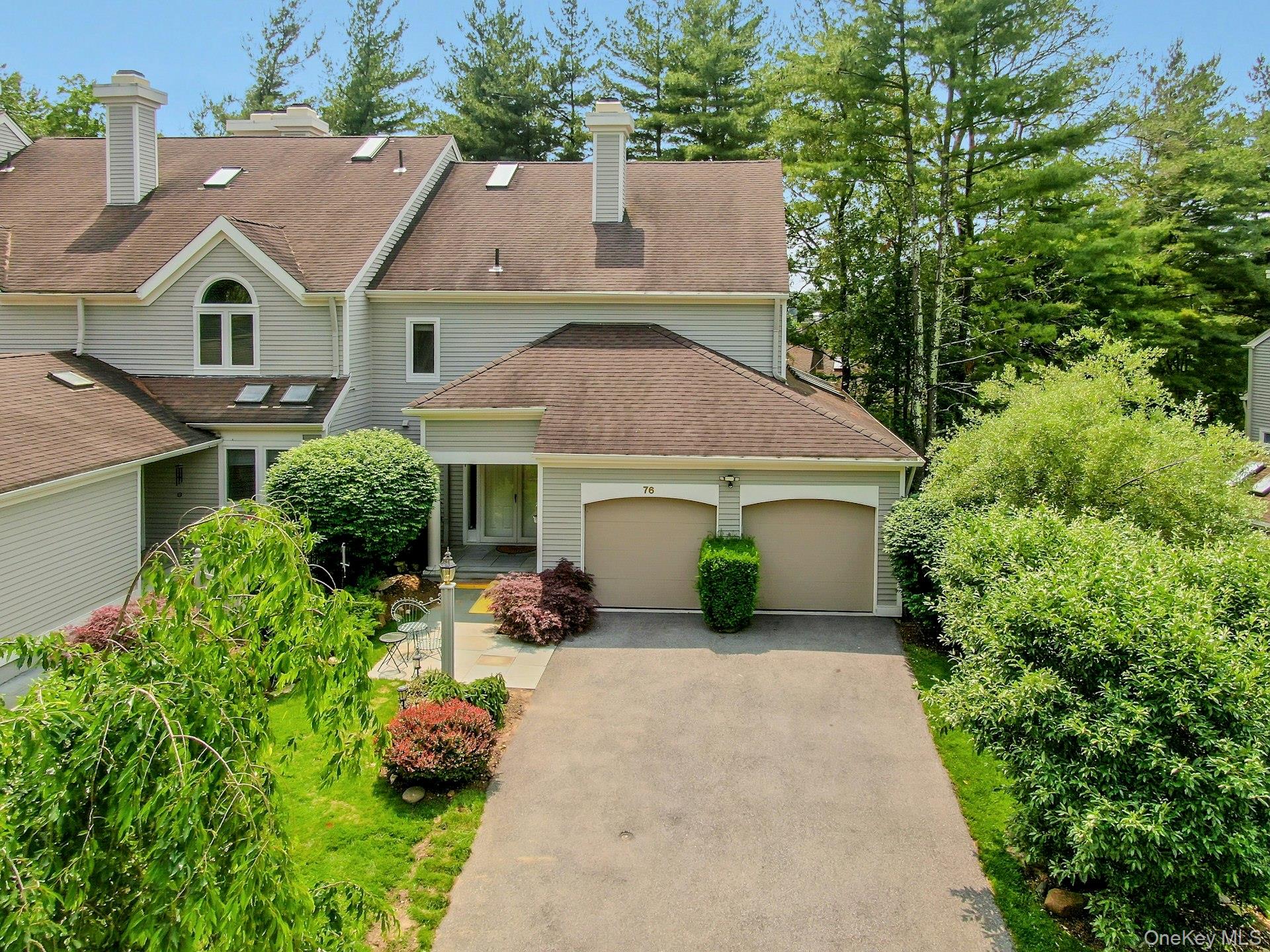 View of front of house with a garage, driveway, a chimney, and a shingled roof