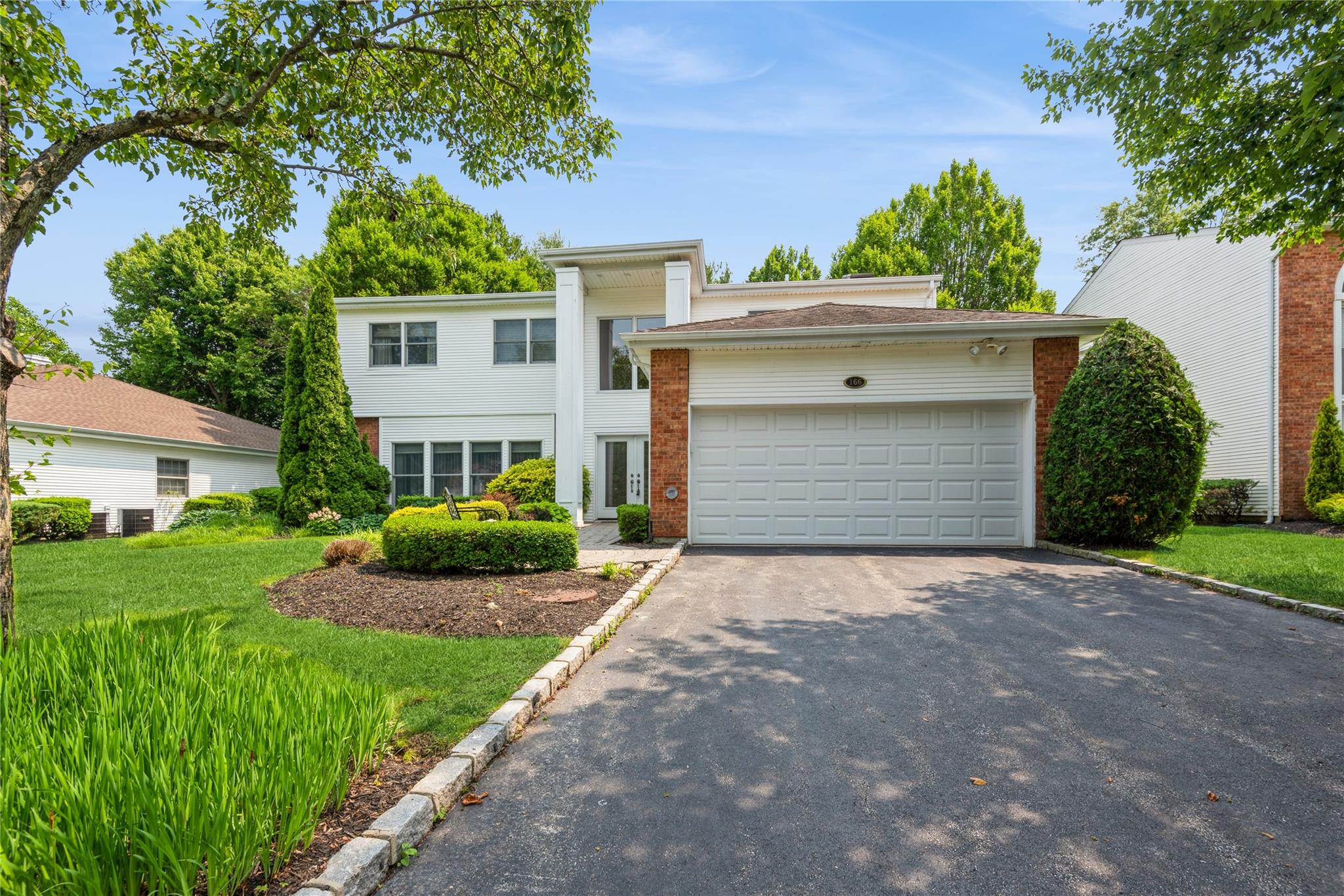 View of front of house featuring asphalt driveway, brick siding, and an attached garage