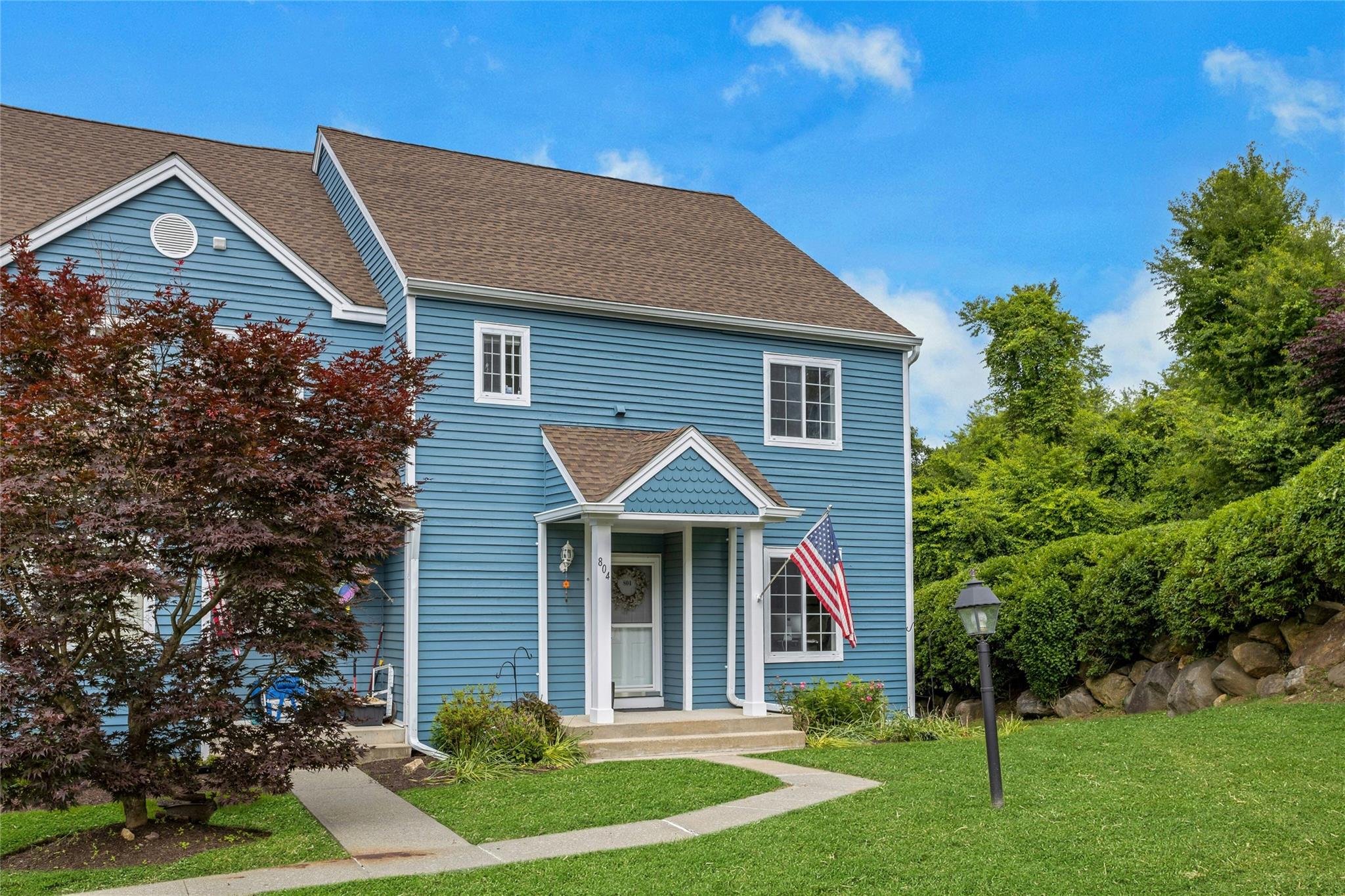 View of front of property featuring a front lawn and a shingled roof