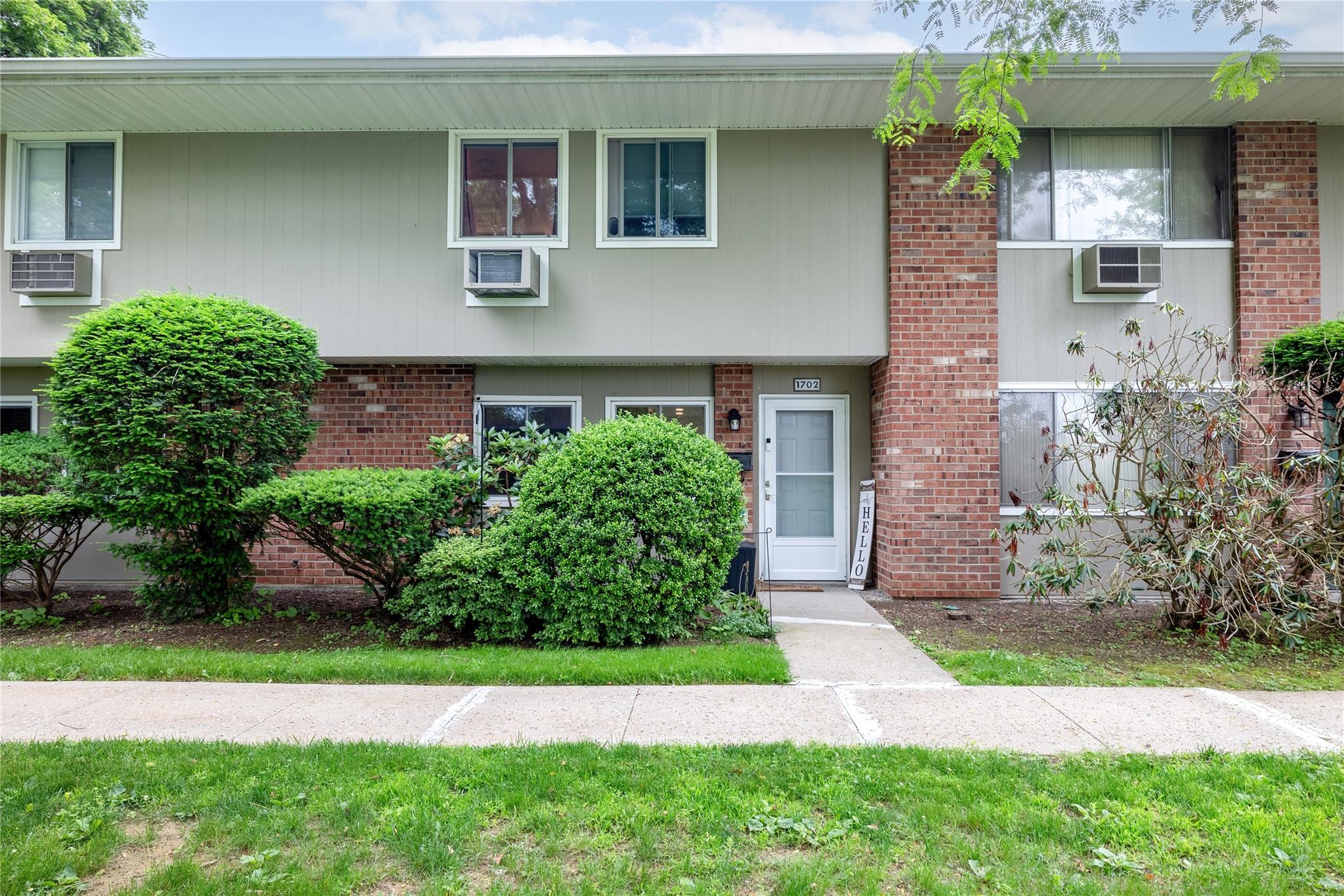 View of property with brick siding and a wall unit AC