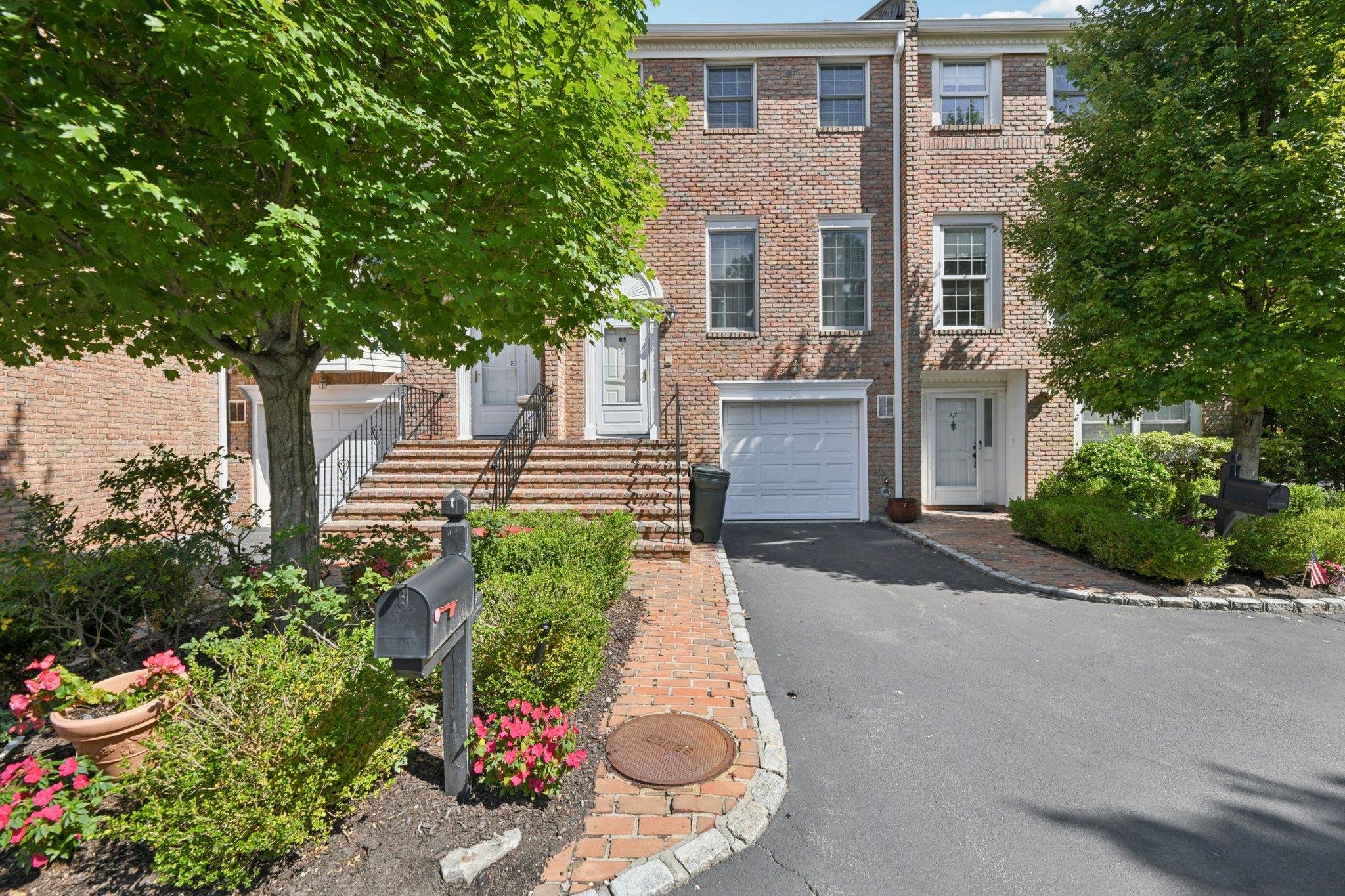 View of front of home with a garage, asphalt driveway, and brick siding