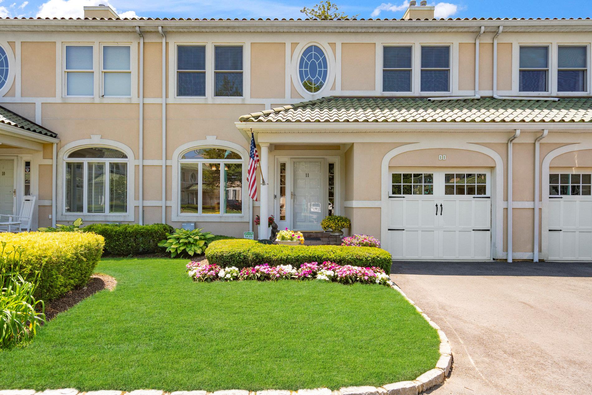 View of front facade with stucco siding, asphalt driveway, an attached garage, a front yard, and a tile roof