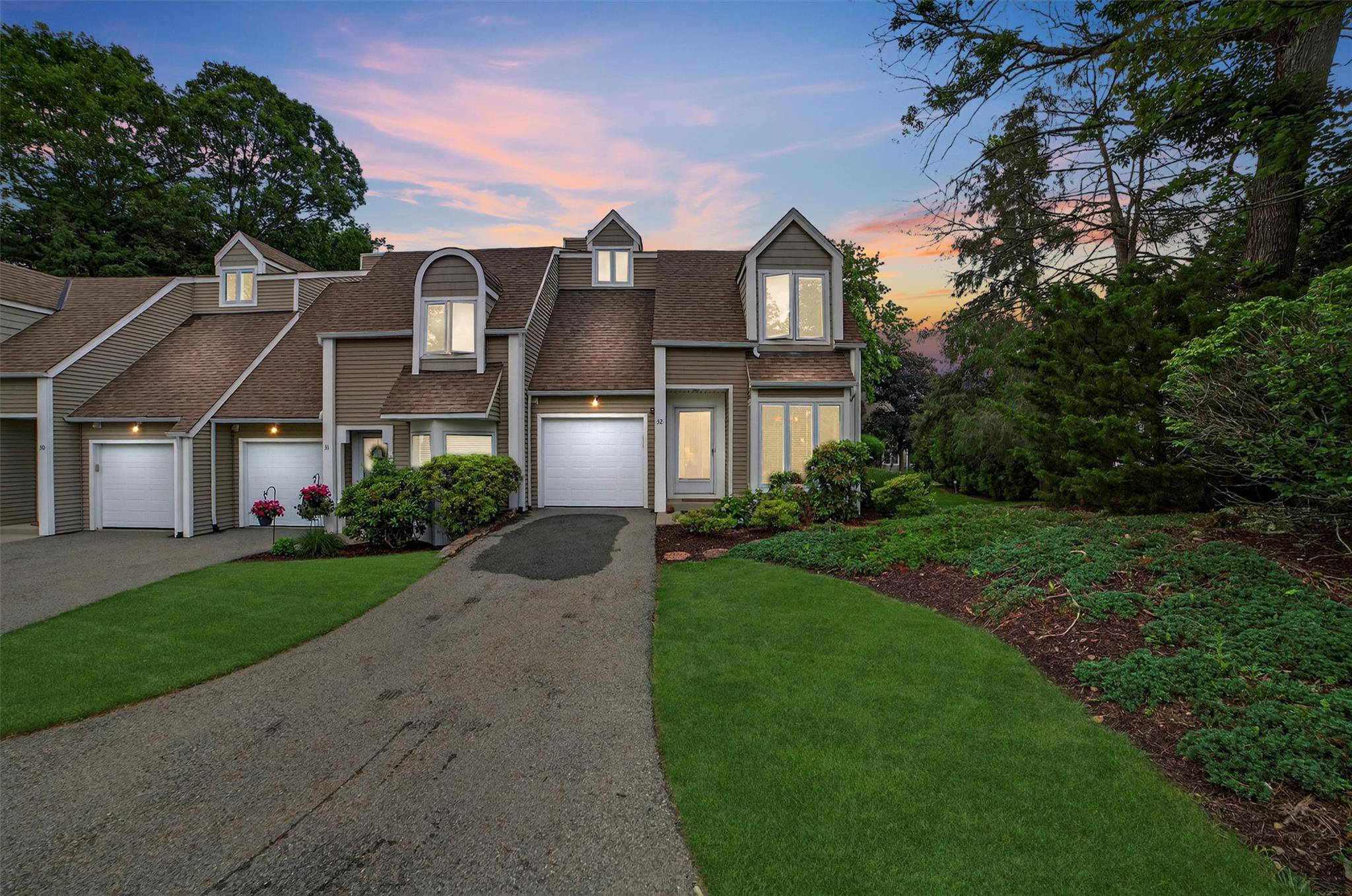 View of front facade with a shingled roof, driveway, a front lawn, and a garage