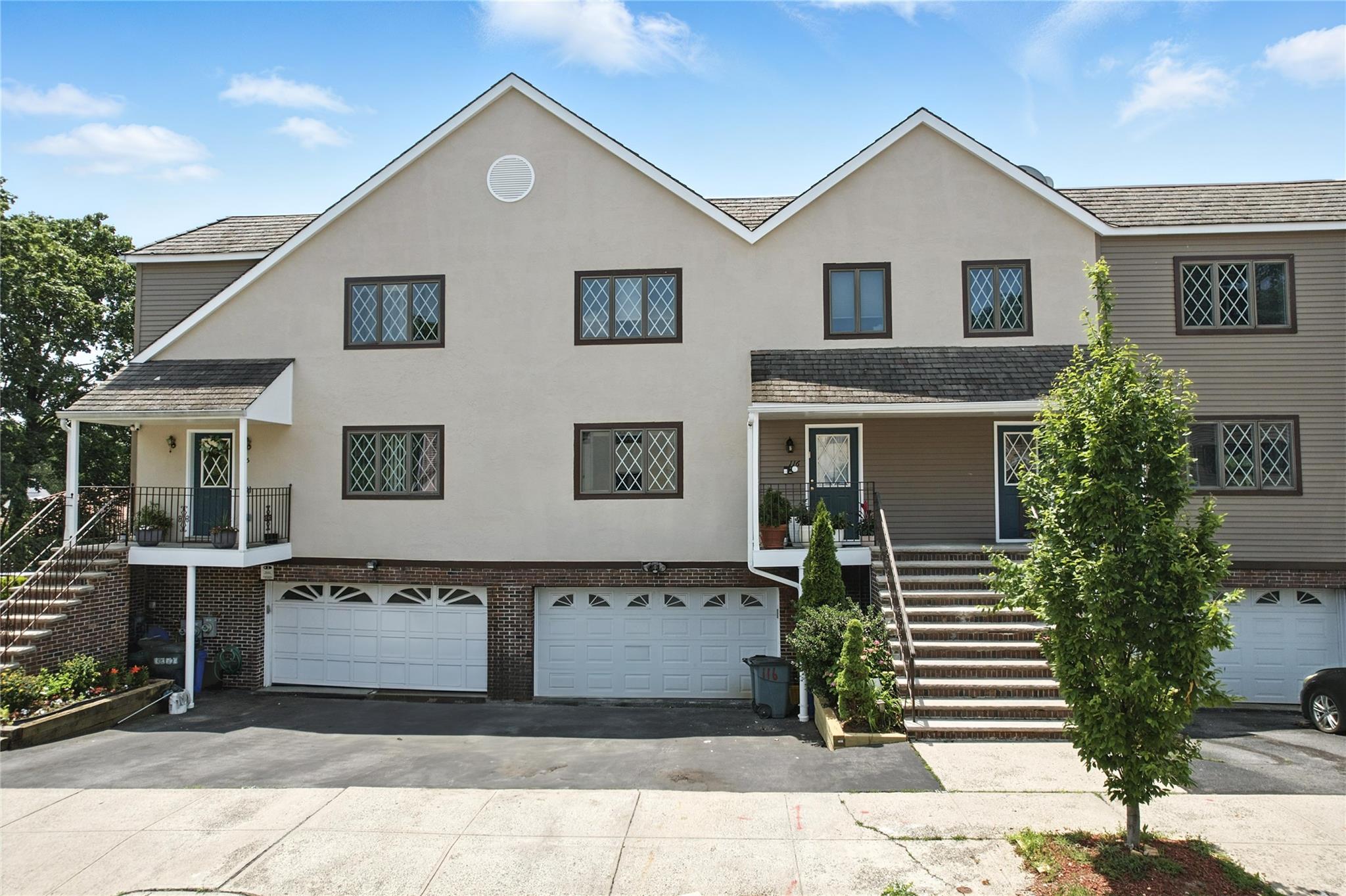 View of property with stairway, asphalt driveway, stucco siding, and a garage