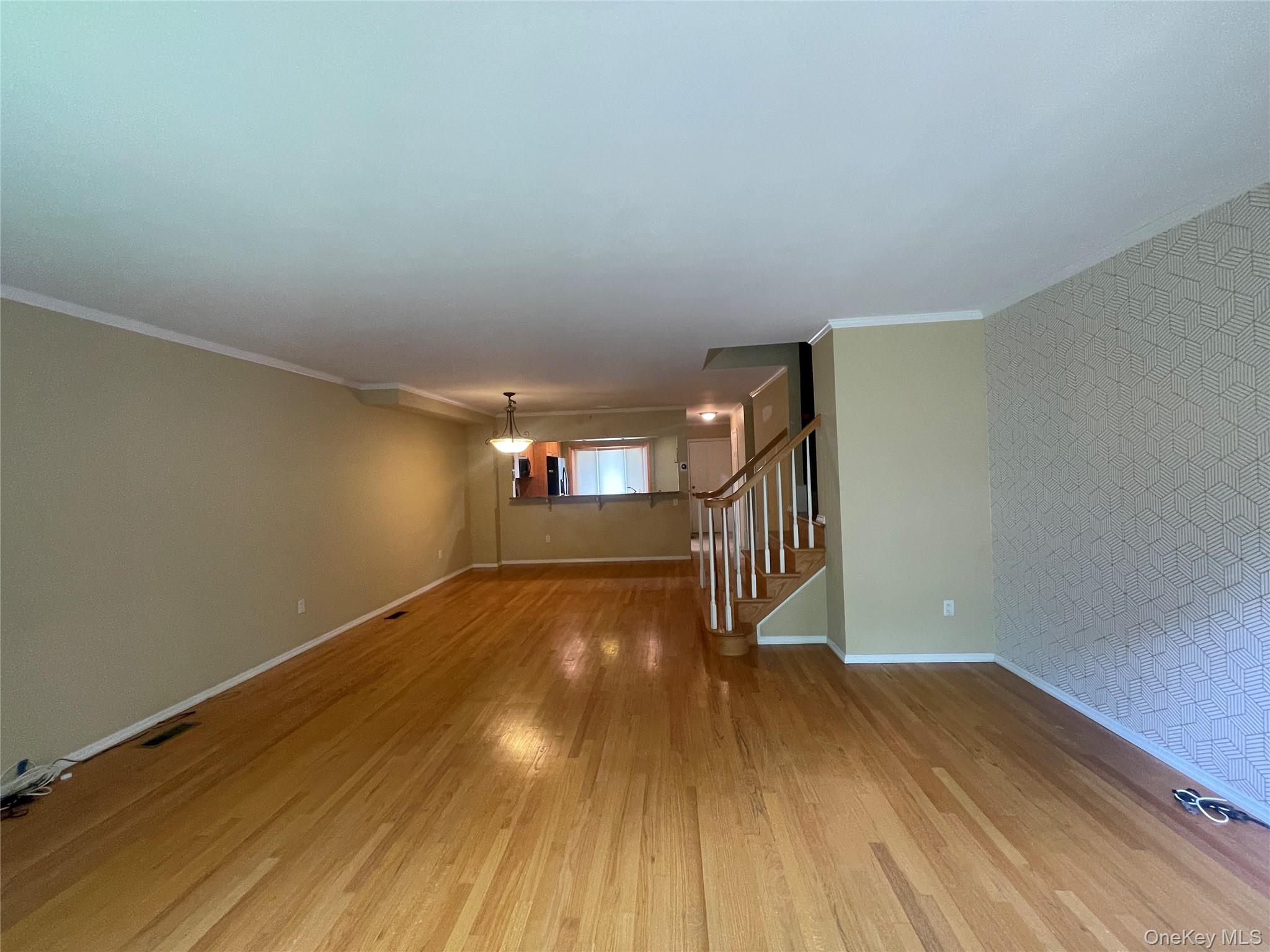 Unfurnished room featuring wood finished floors, crown molding, and stairs