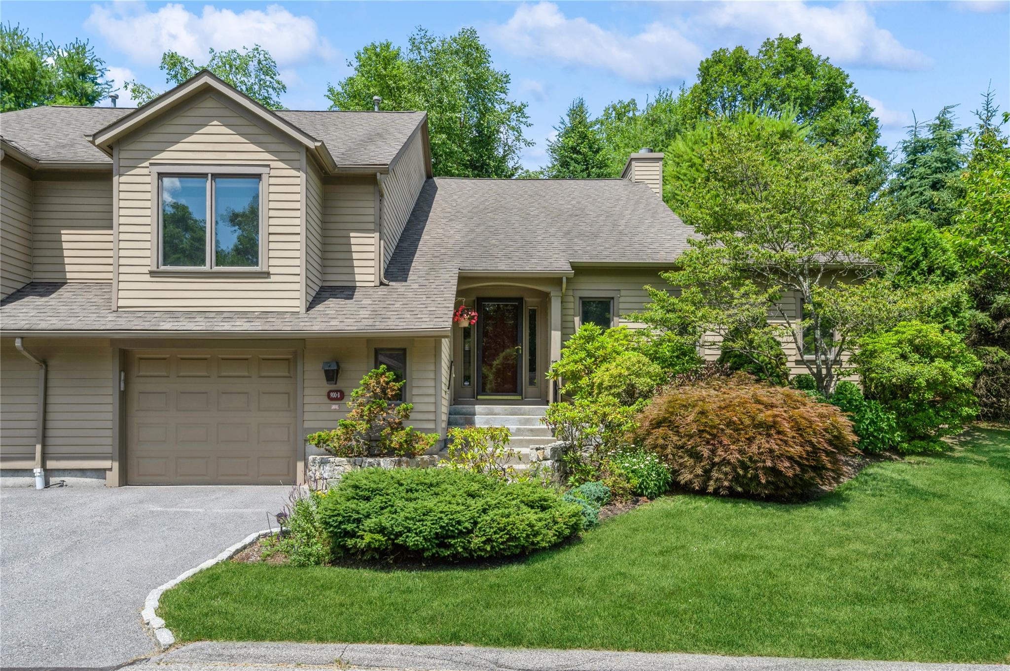 View of front of house featuring roof with shingles, a front yard, an attached garage, a chimney, and driveway