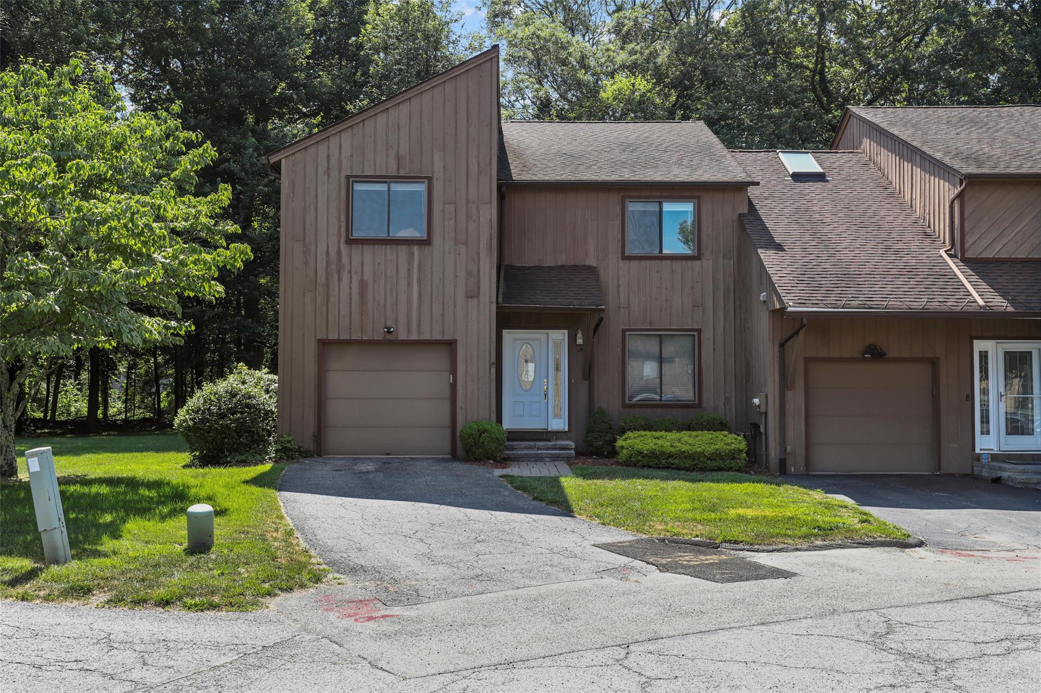 View of front facade featuring a shingled roof, asphalt driveway, and a front lawn