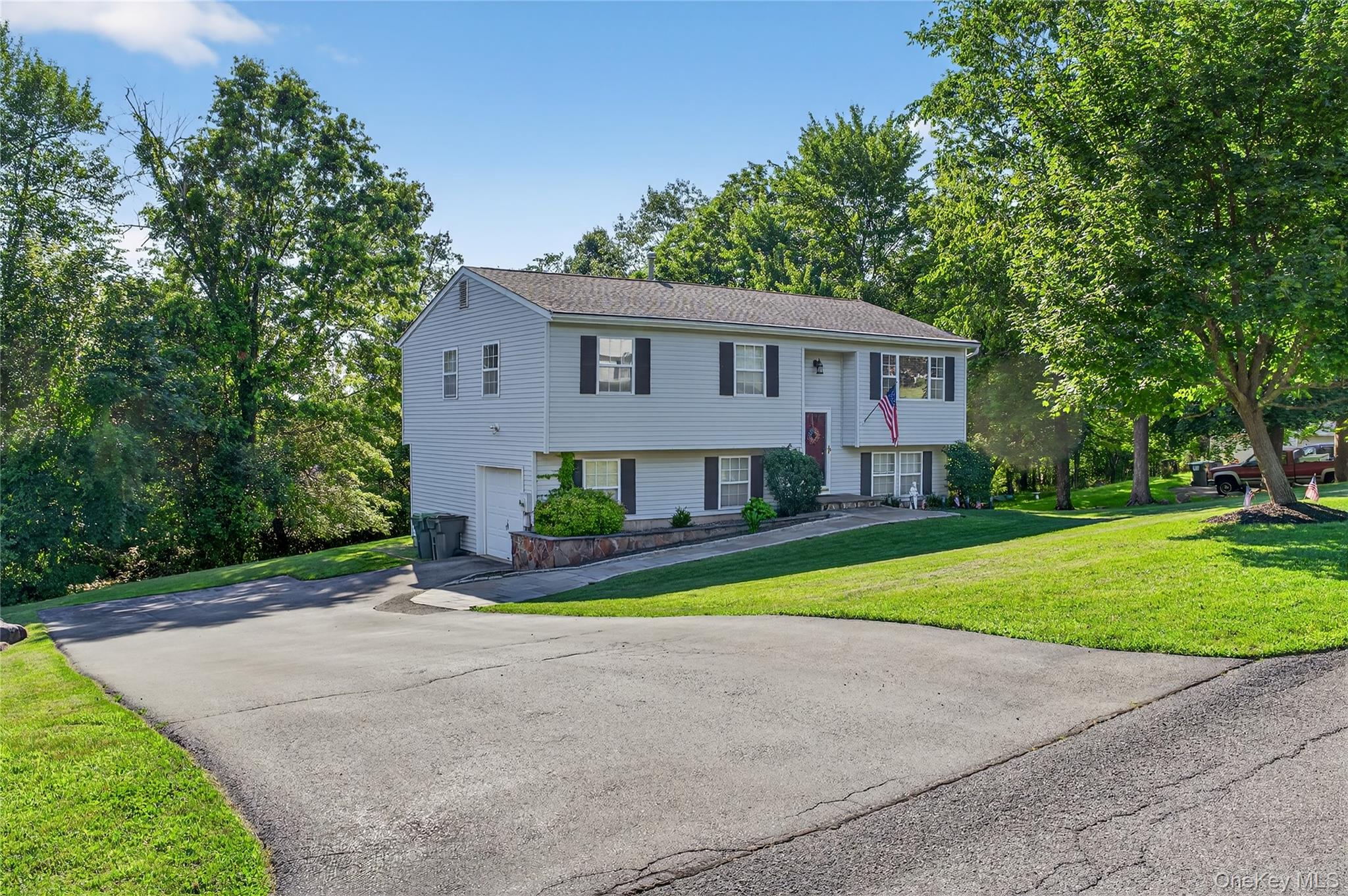Bi-level home with a garage, asphalt driveway, and a front lawn