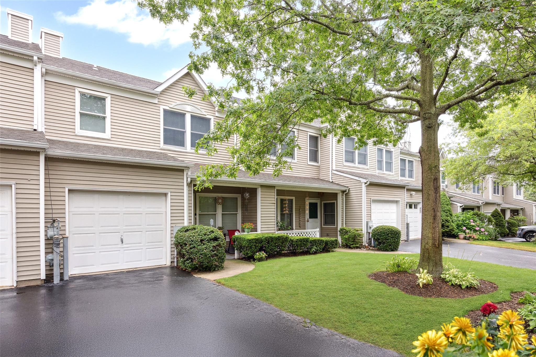 Traditional-style home with an attached garage, a front yard, asphalt driveway, and a shingled roof
