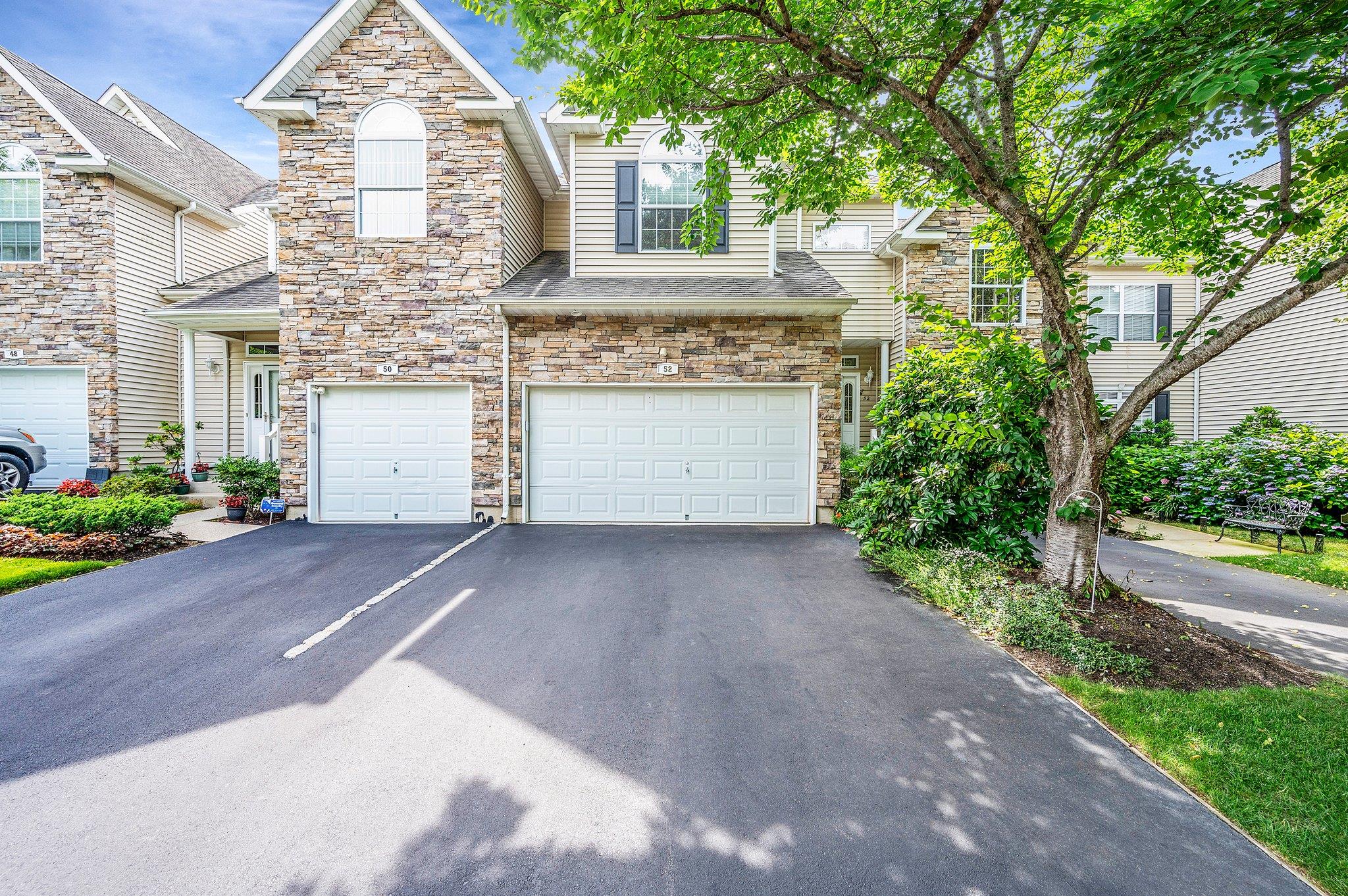 View of front of house featuring asphalt driveway, stone siding, and an attached garage