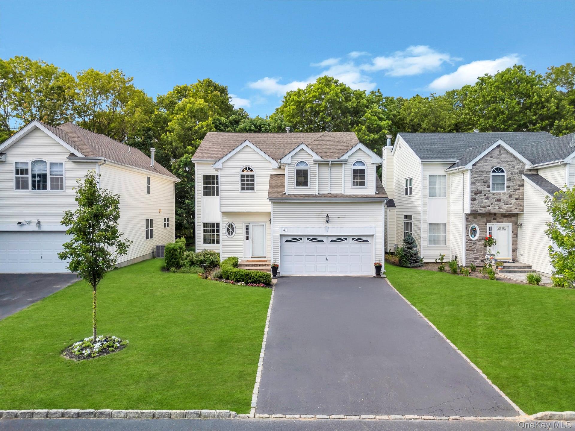 View of front of home featuring a garage, asphalt driveway, and a front lawn